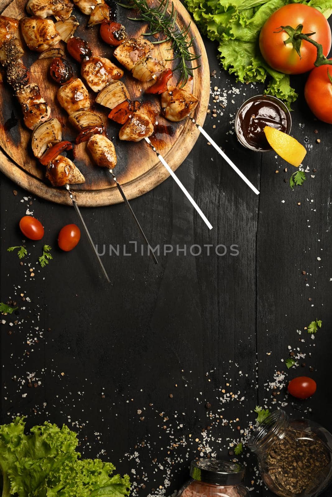 Delicious barbecue skewers with fresh vegetables on black rustic wooden table.