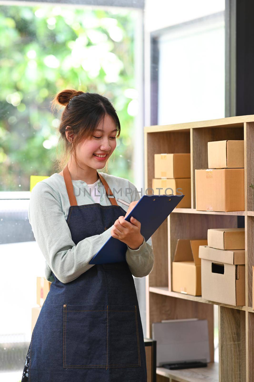 Startup small business owner in apron working at warehouse for online seller. Online selling, E-commerce concept.