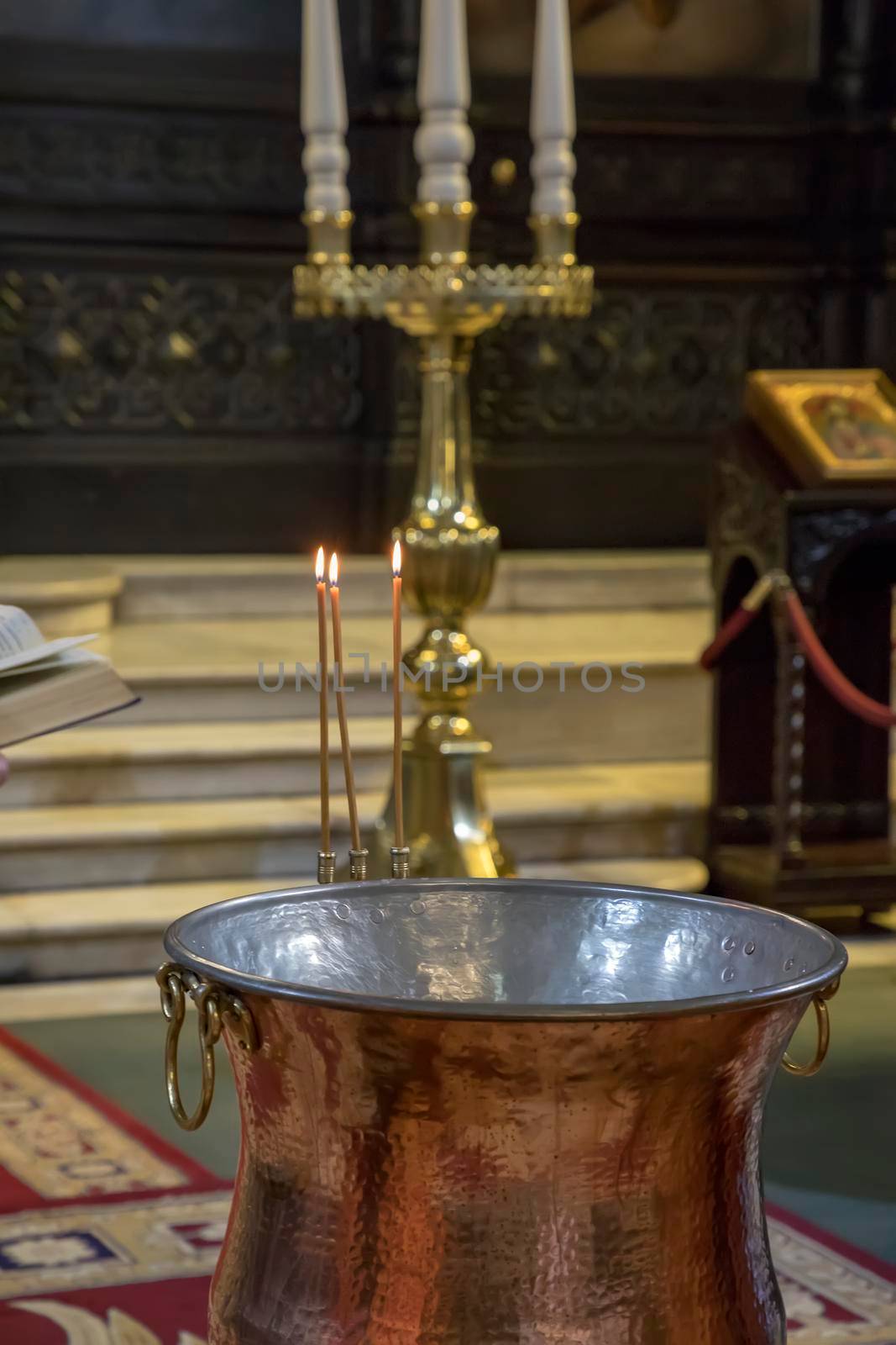Christening in the church. Church utensils in the Orthodox church. A big bowl of water for the baptism of a baby with wax candles.