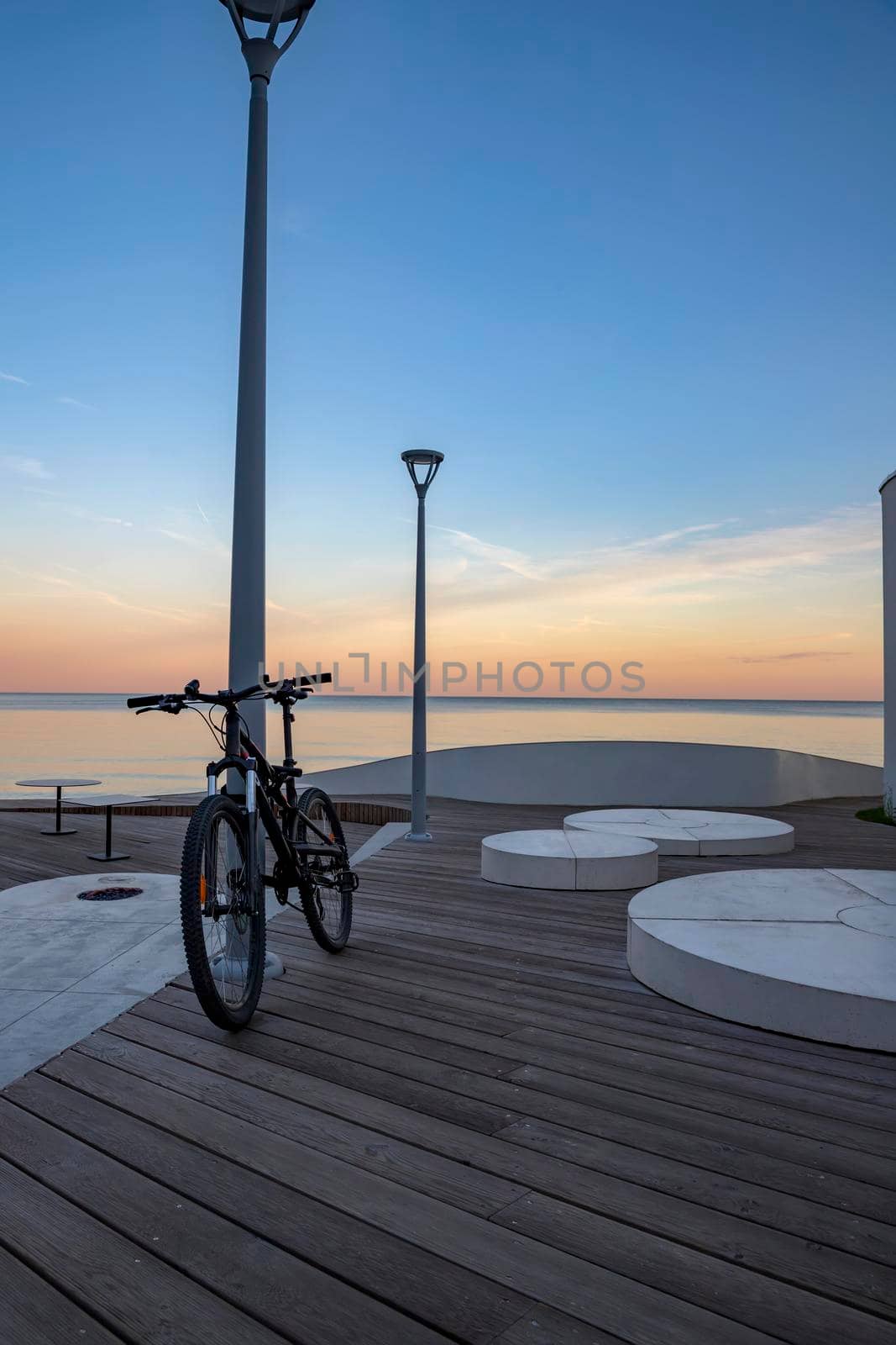 Idyllic scene of a bicycle standing near the sea propped on a pillar with blue sky as background by EdVal