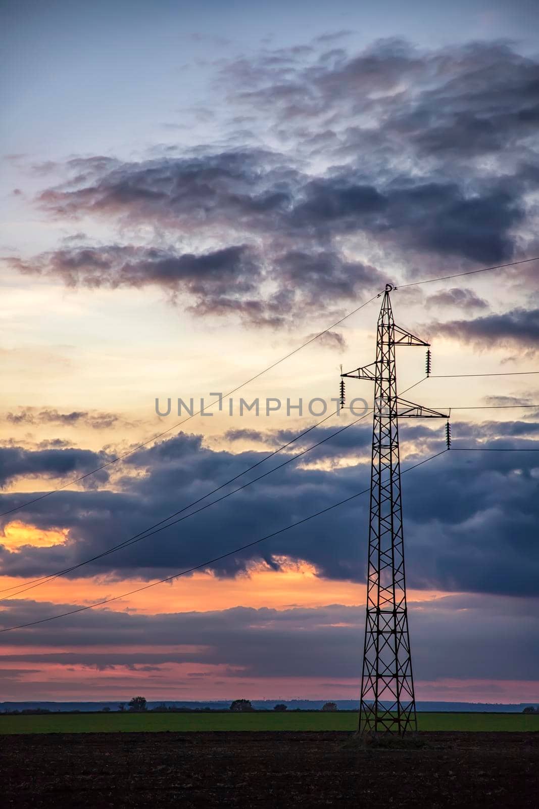 Poles and overhead power lines silhouettes in the dusk. Electricity generation and distribution. Electric power industry and nature concept by EdVal