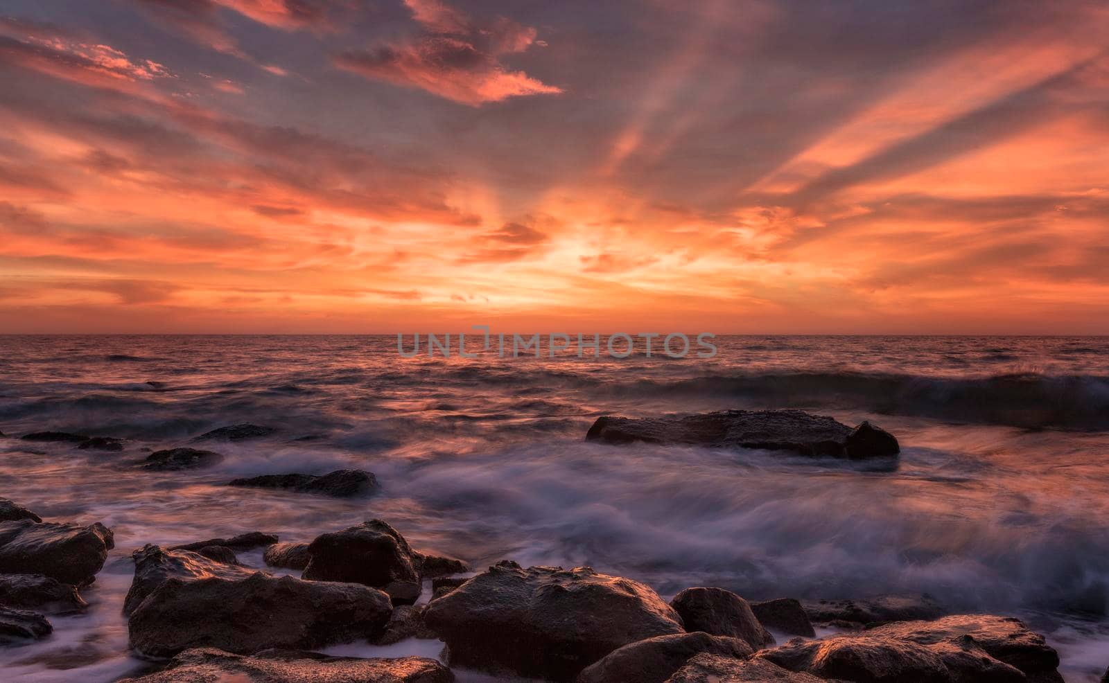 First light. Stunning seascape with motion blur and flowing waves at the rocks