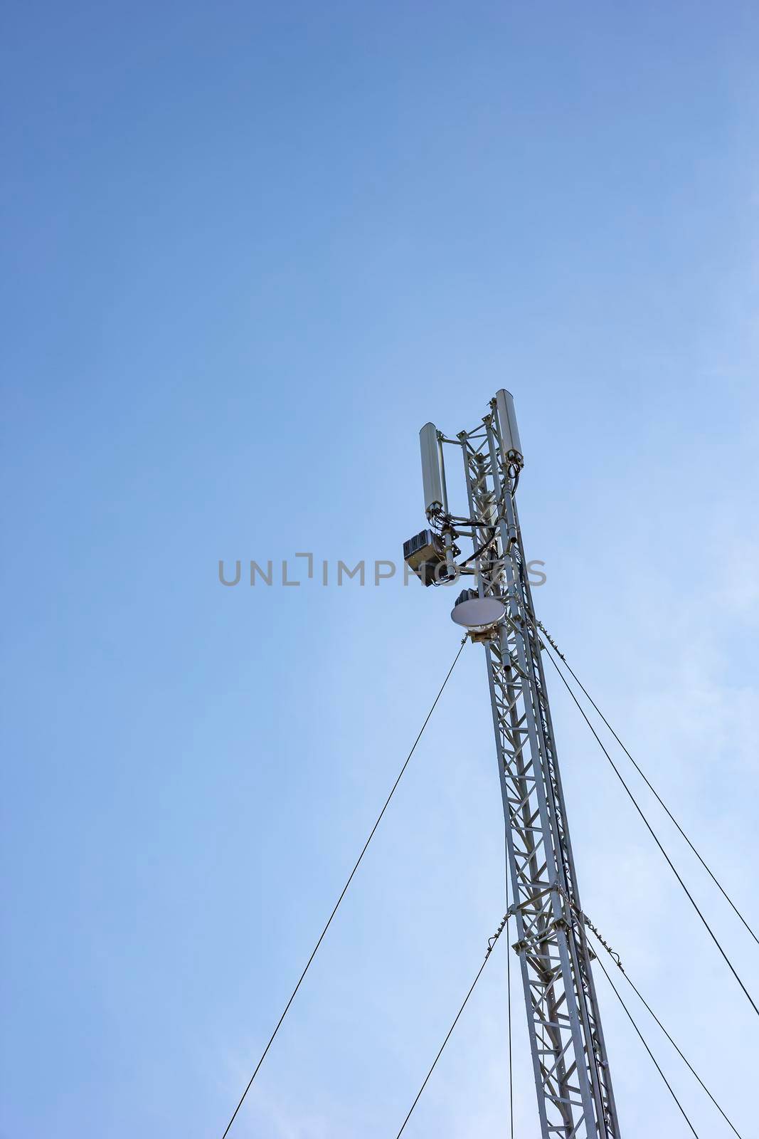 Antenna cellular tower and blue sky. Vertical view
