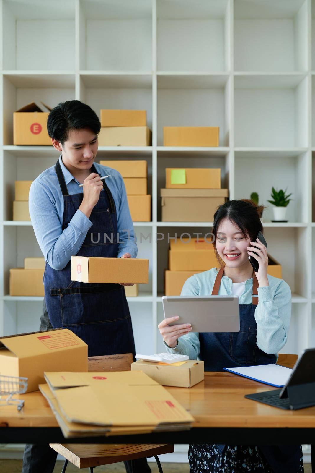 Asian couples doing SMEs deliver their products online to customers who order products via the Internet, helping to sell happily : Work From Home online.