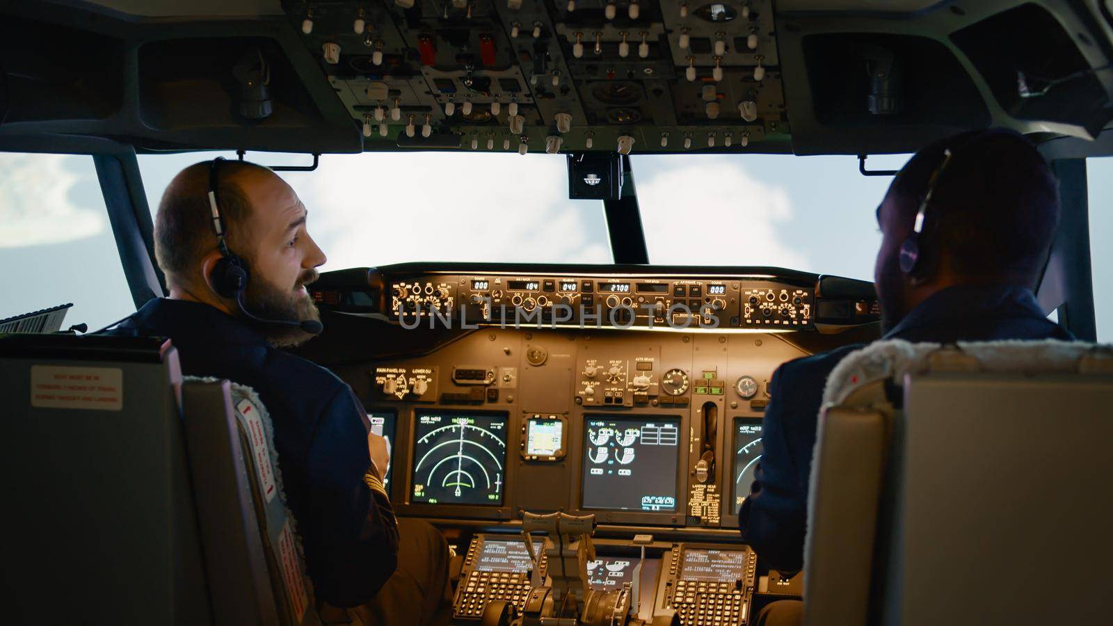 Diverse team of captain and copilot using dashboard command to takeoff and fly airplane. Pushing buttons to switch altitude and longitude on control panel in cockpit. Handheld shot.