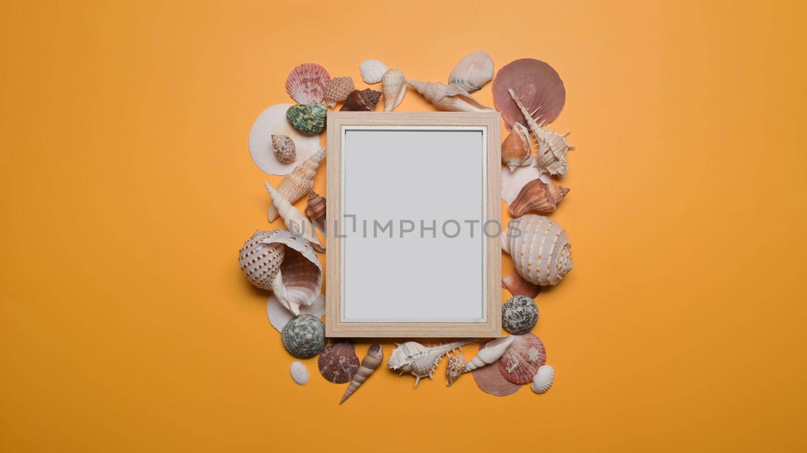 Empty picture frame with seashells on yellow background. Travel, summer and holiday concept. by prathanchorruangsak