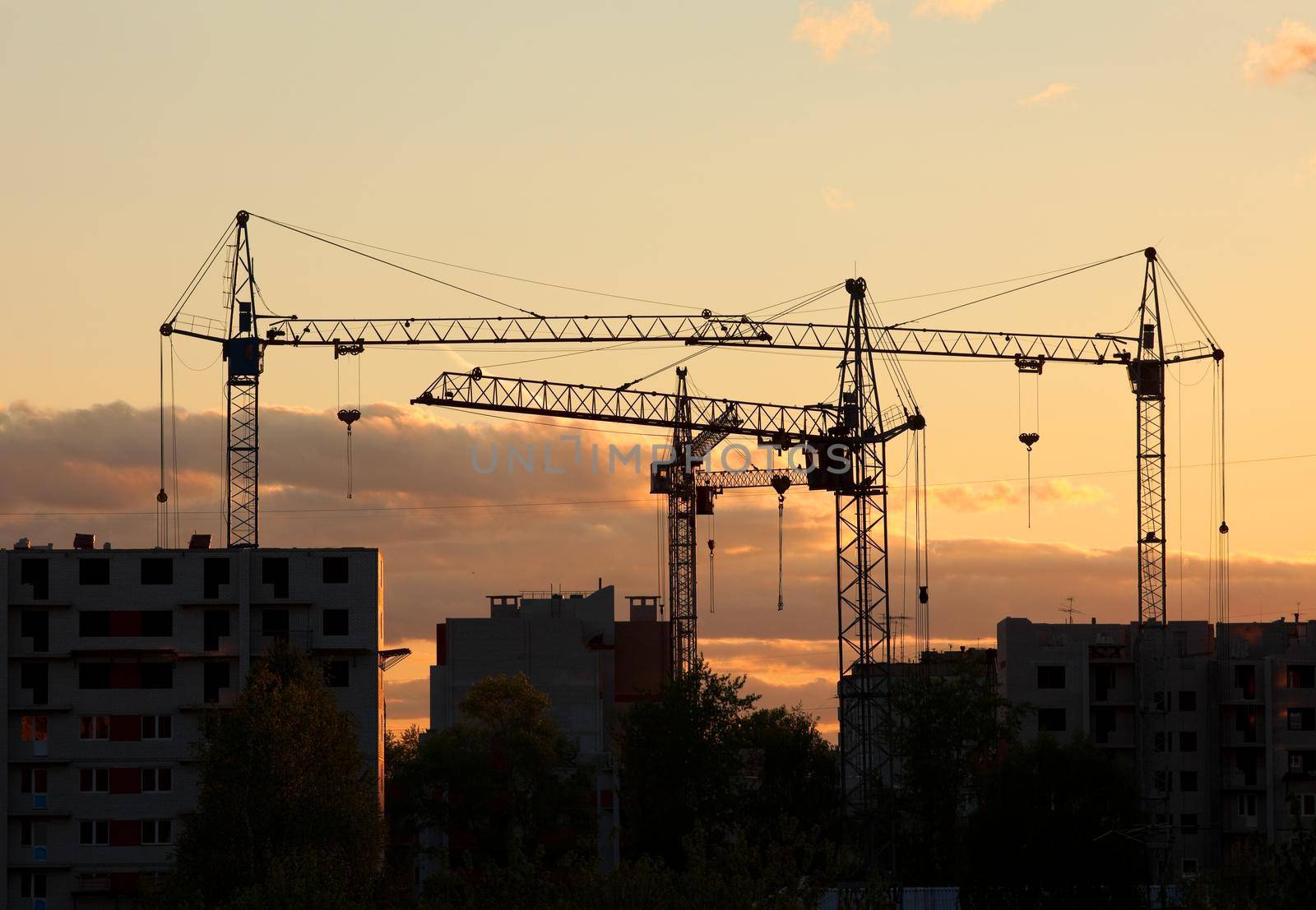 cranes on construction site house at sunset by rivertime