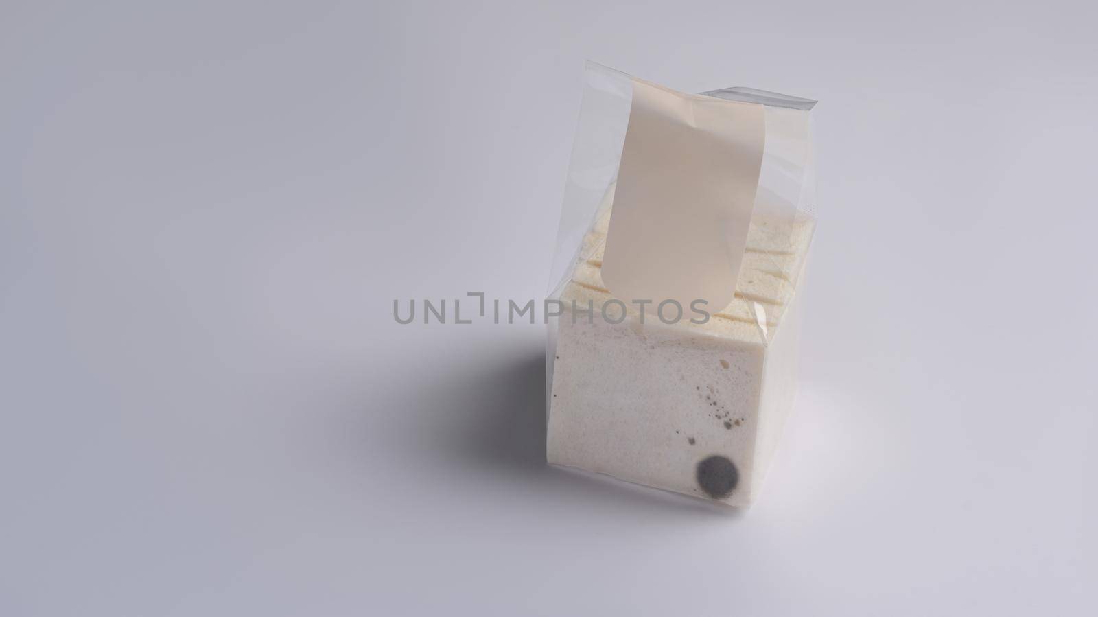 Moldy bread in package on white background.