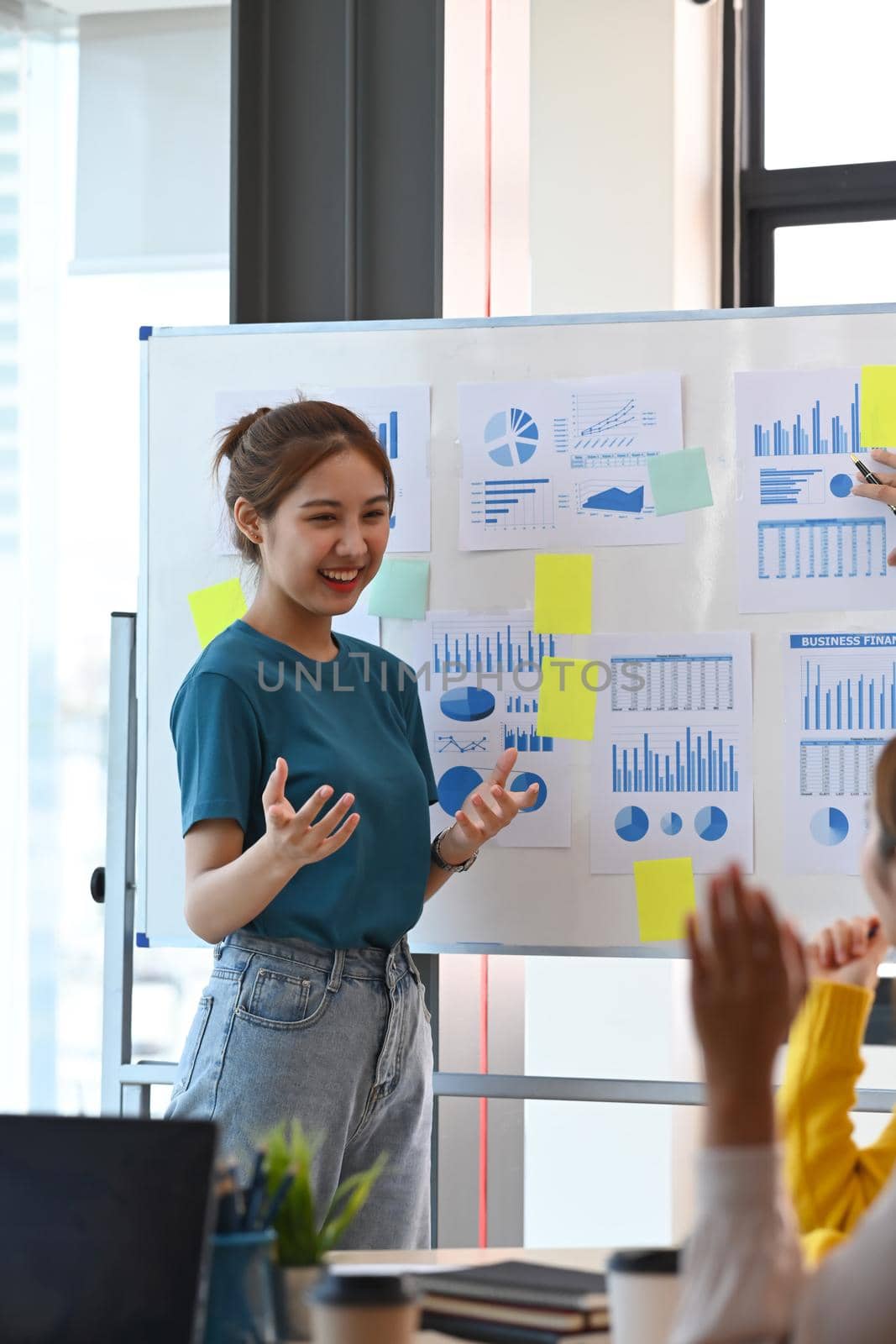 Cheerful young woman giving presentation new project to clients at bright modern office.