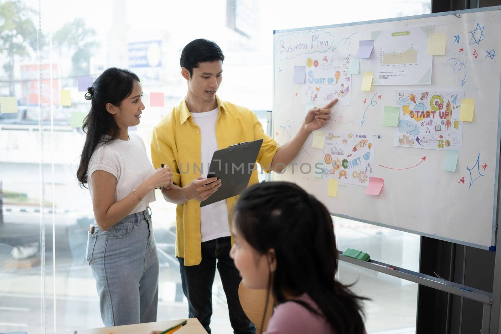 Three business startup employee discussion on working board in modern office.