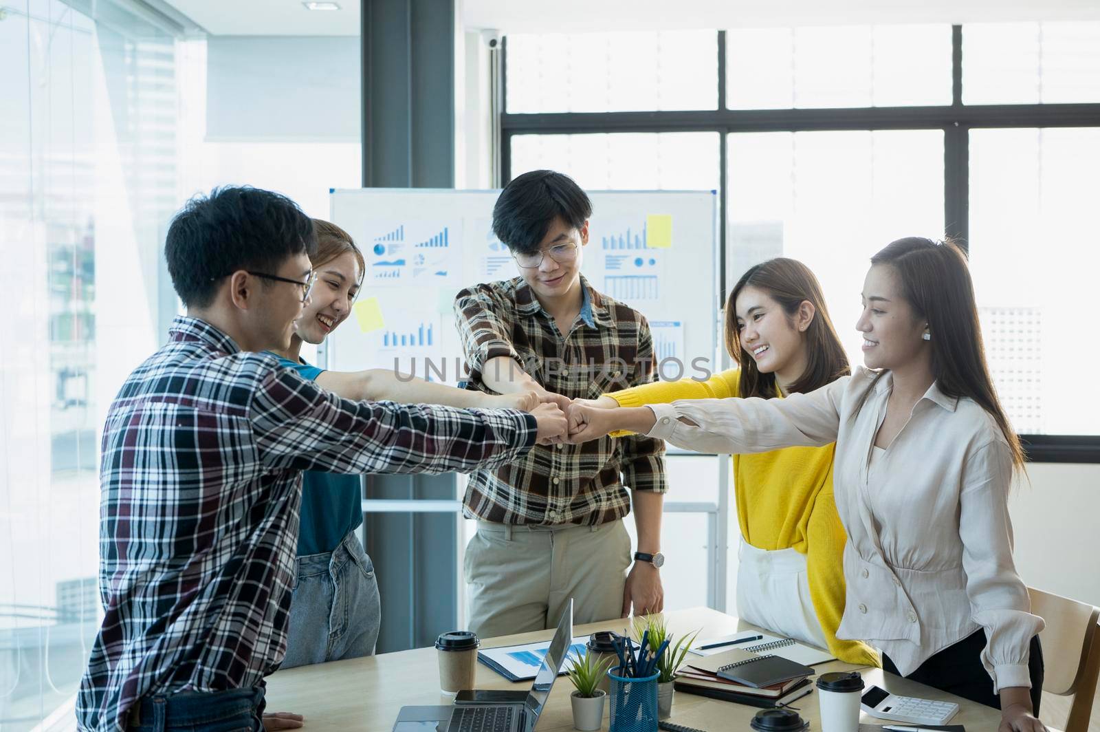 Businesspeople joining fists each other, showing support and team spirit together, celebrating corporate achievement. by prathanchorruangsak