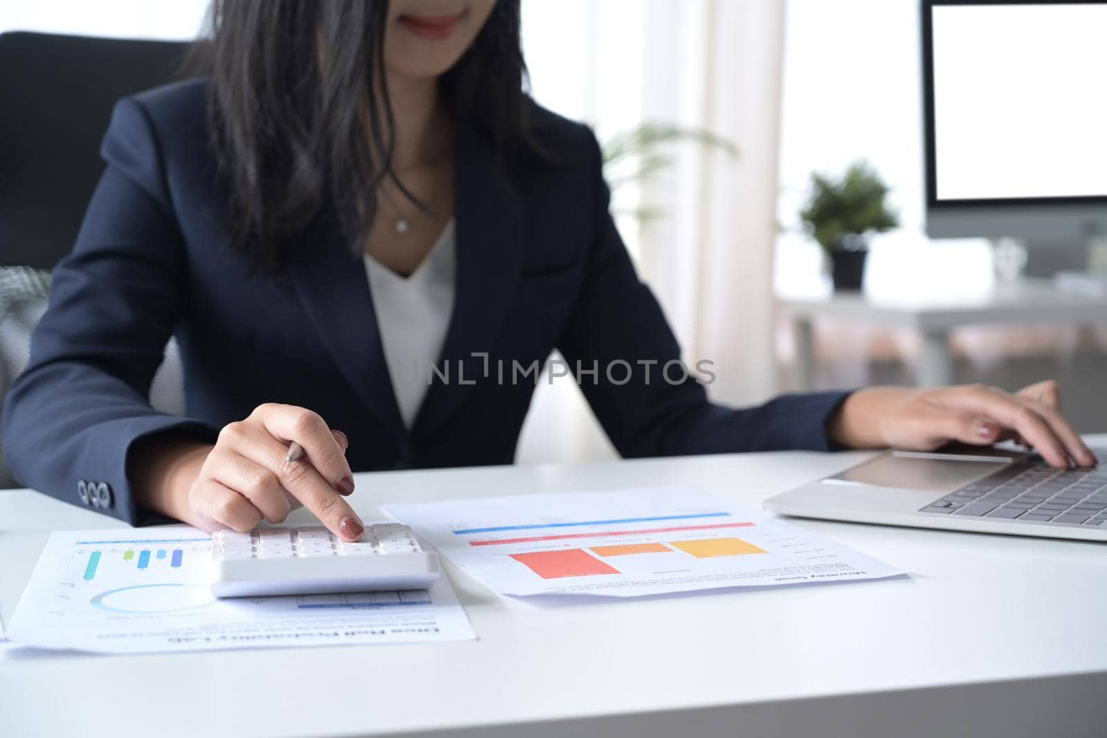 Professional investor using calculator and checking financial reports at her workplace.