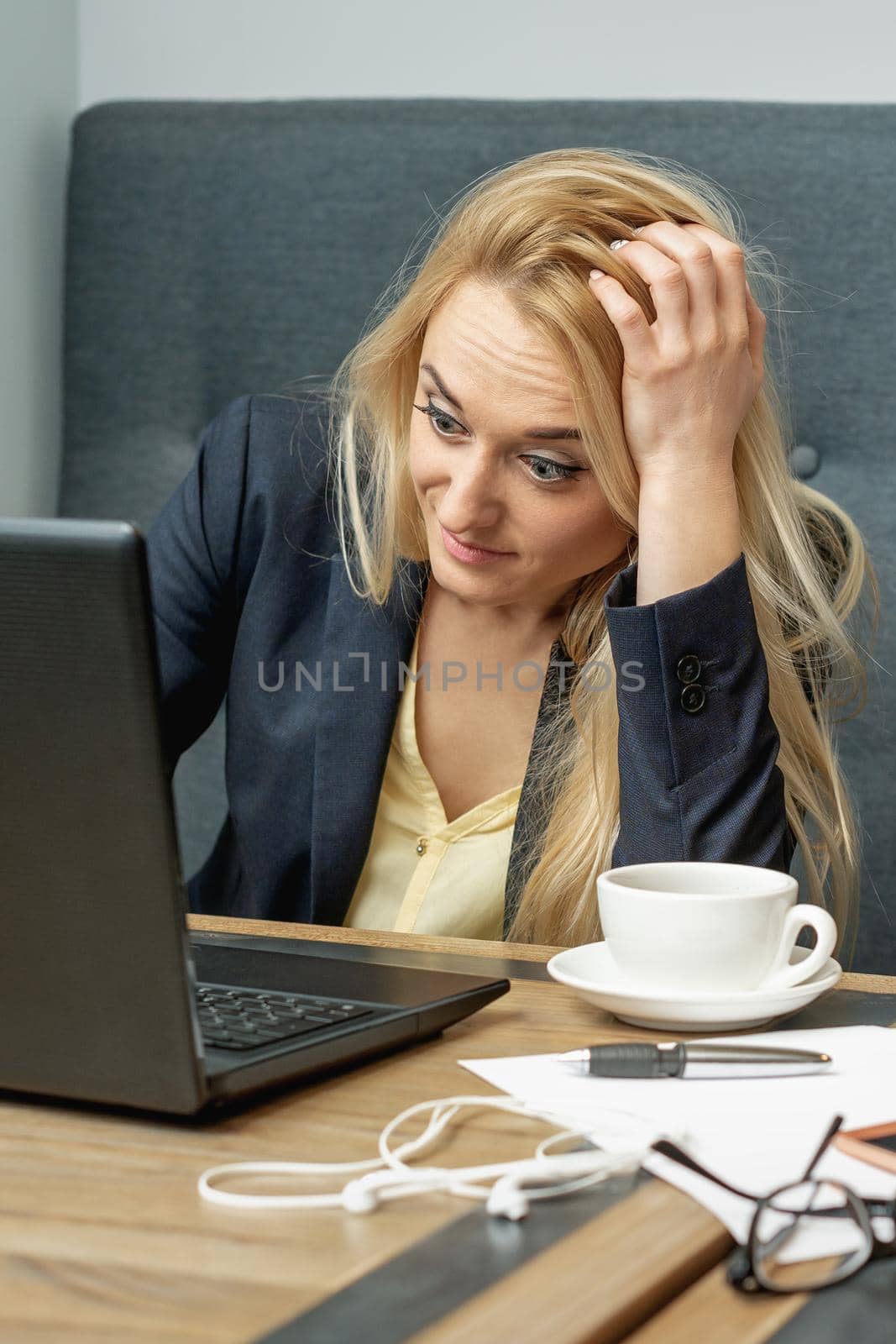 Young female office worker looking at laptop screen looks surprised dissatisfied at home office.