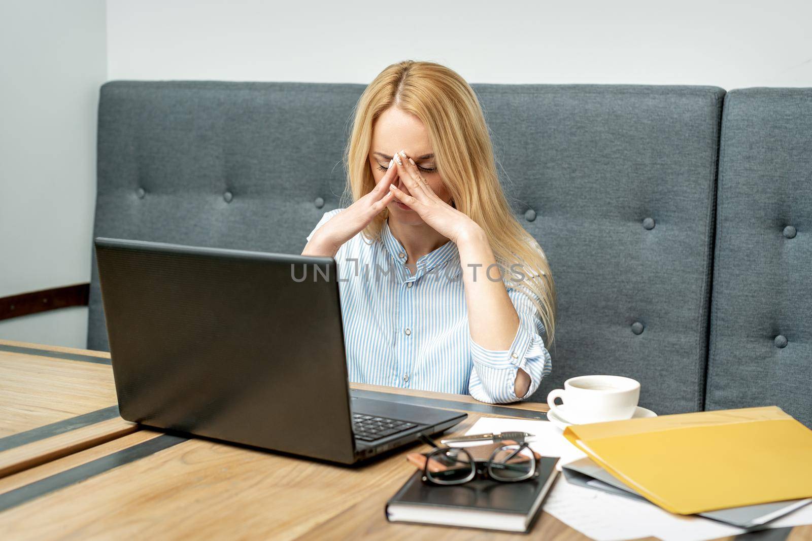 Tired young business woman sitting in front of laptop at office.