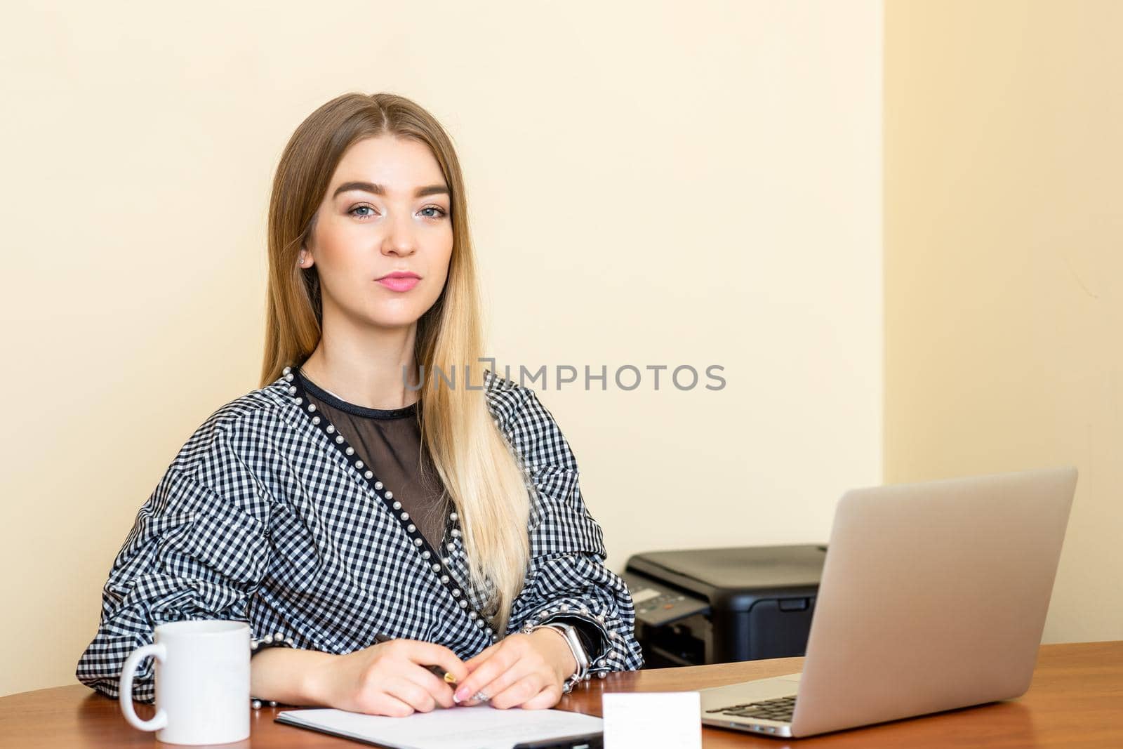 Portrait of a casual business woman sitting at her workplace in home office.