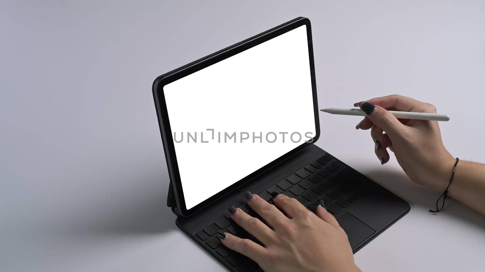 Cropped shot woman holding stylus pen pointing on digital tablet screen.