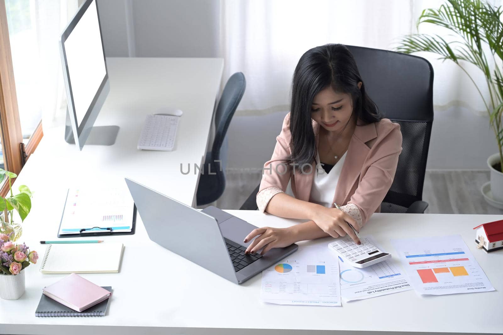 Female professional accountant using calculator and preparing annual financial report at workplace.