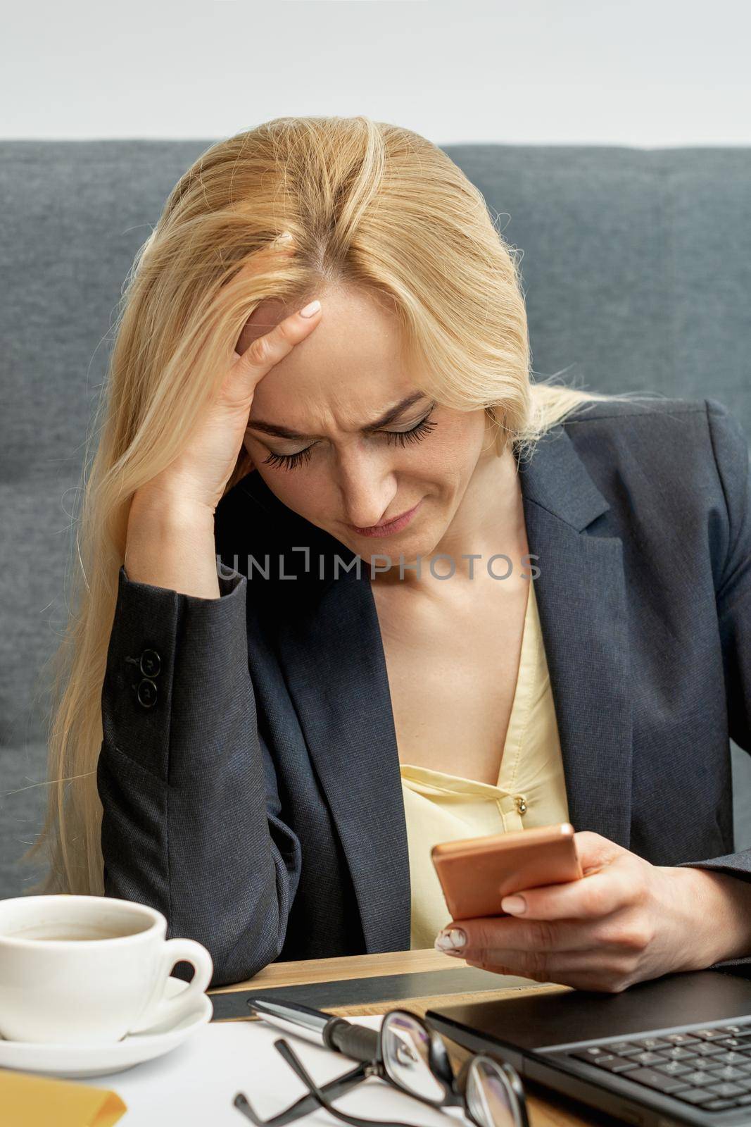 Frustrated young woman looking surprised working on smartphone at home office.