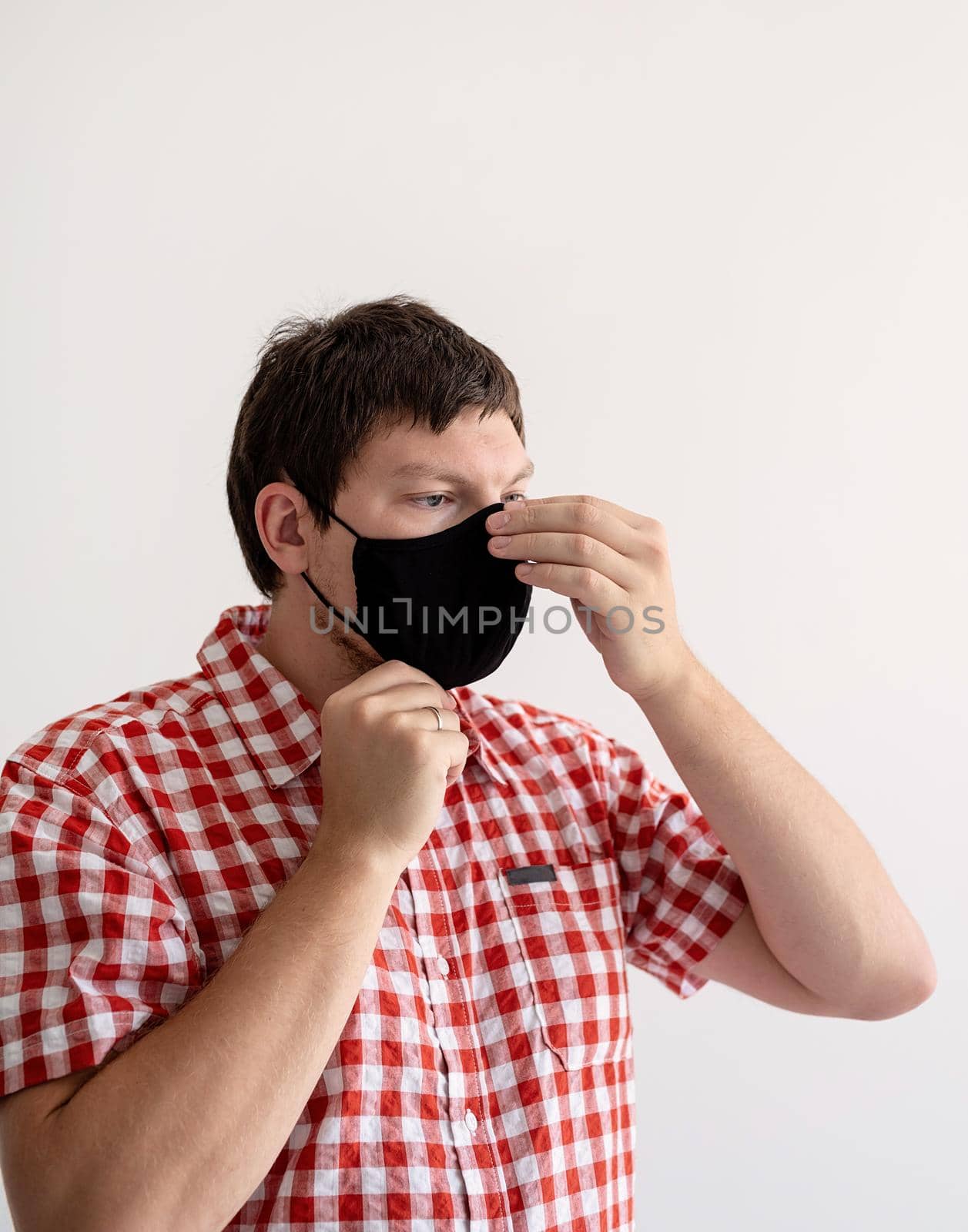 Healthcare concept. Young man putting on protective mask on white background, portrait, close up. Copy space