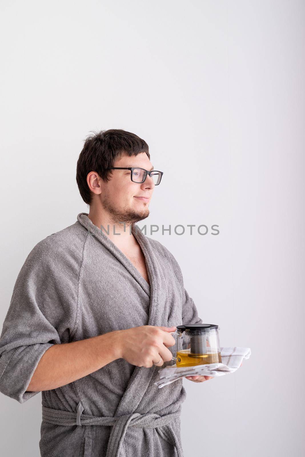 Making tea. Portrait of man in bathrobes holding teapot with green tea