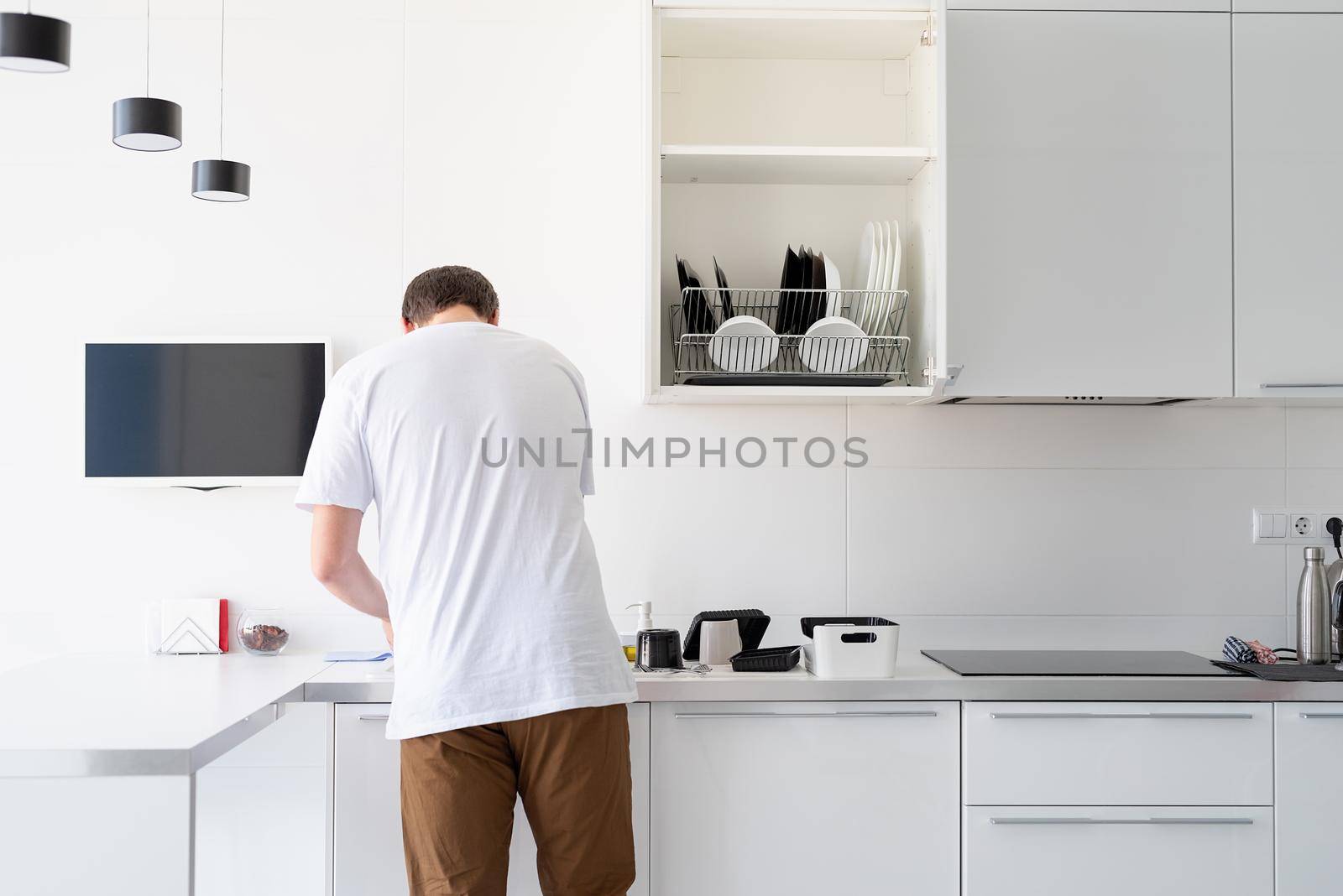 Man in white t shirt washing dishes in the kitchen by Desperada