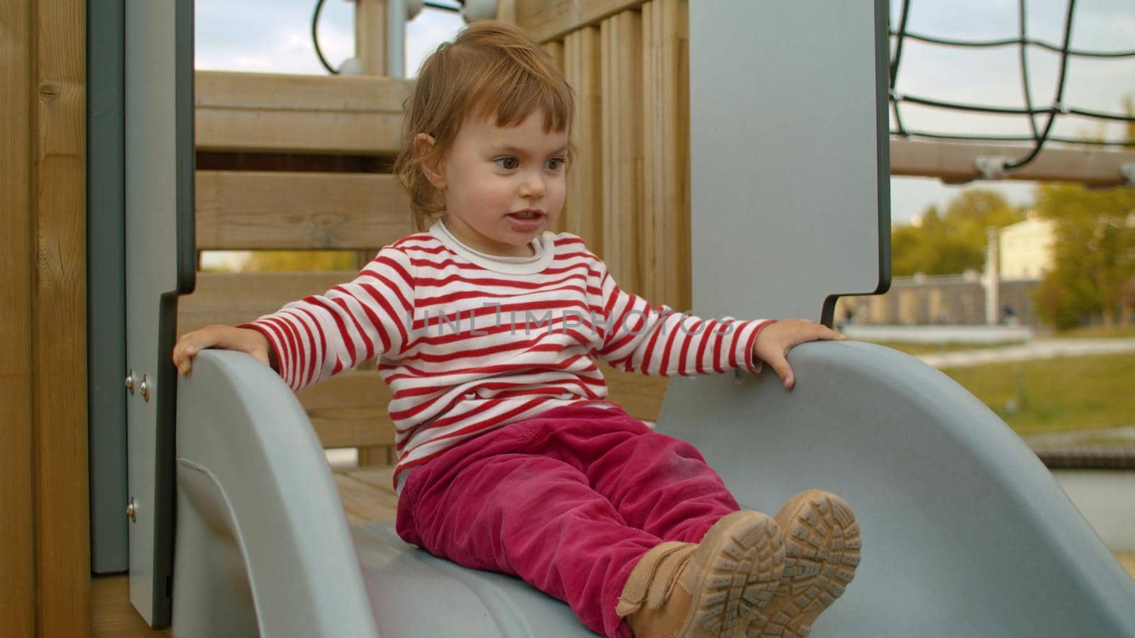 Little girl sitting on a top of a slide by Chudakov