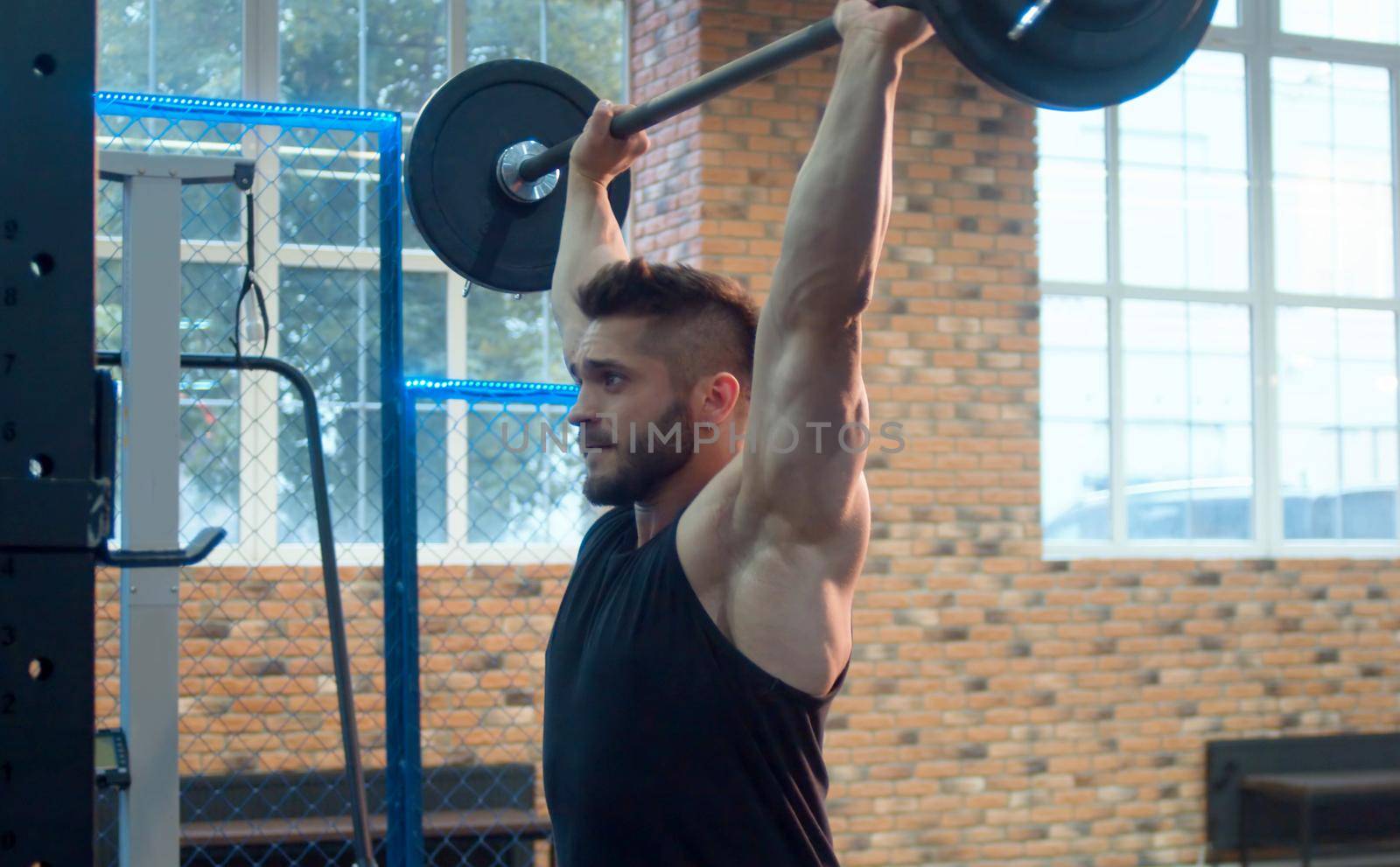 The male athlete lifting barbell. Bodybuilder in the gym