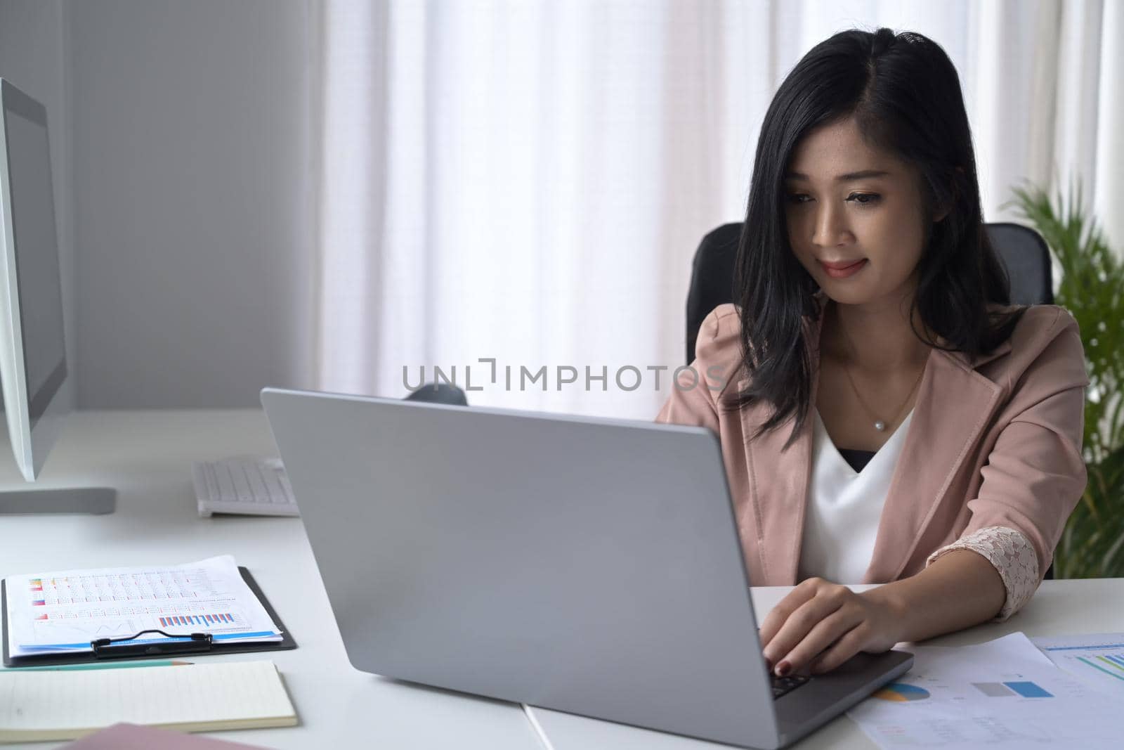 Pretty young woman using laptop computer at modern office.