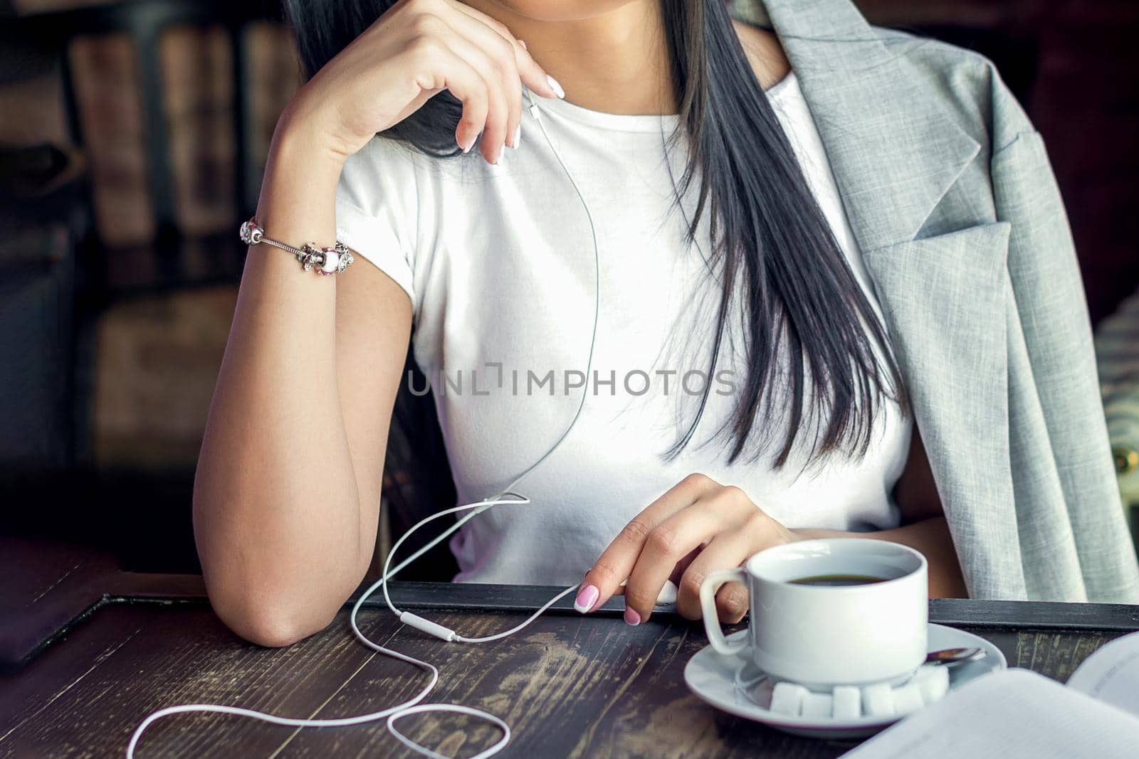 Beautiful caucasian woman is listening music through headphones with cup of coffee in the cafe.