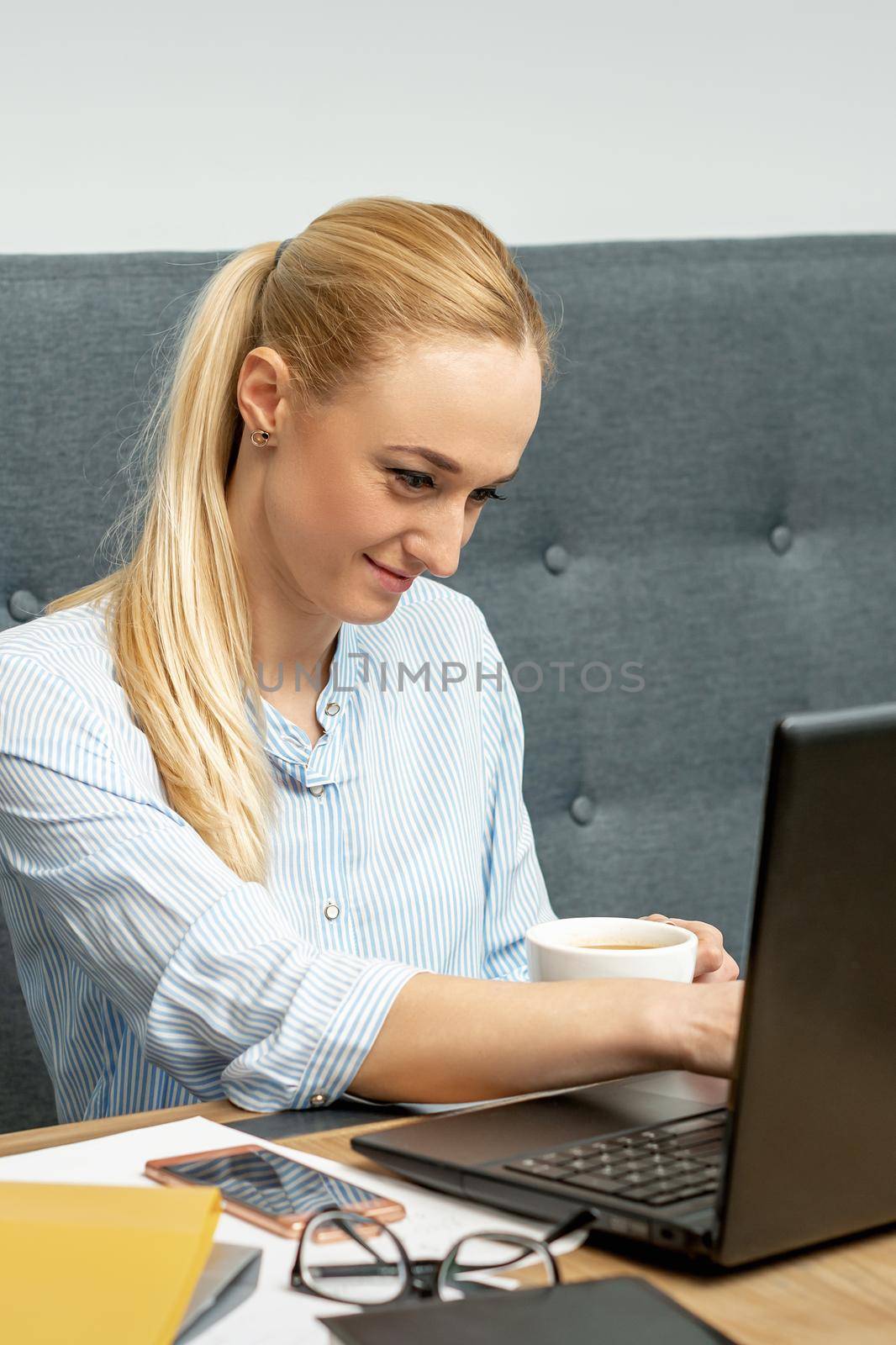 Woman is working on laptop at home office. by okskukuruza