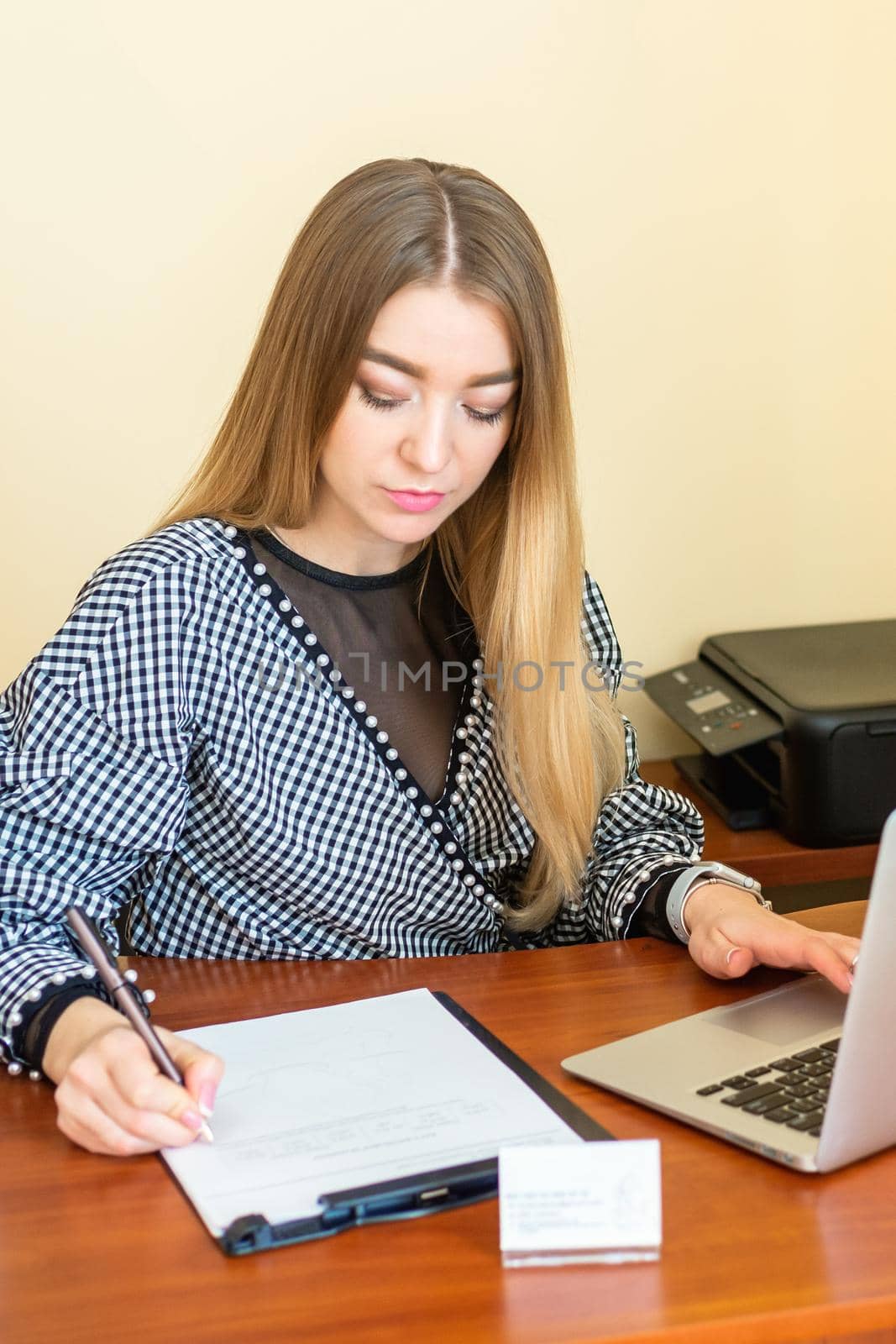 Business woman is writing on a document with laptop at home office.