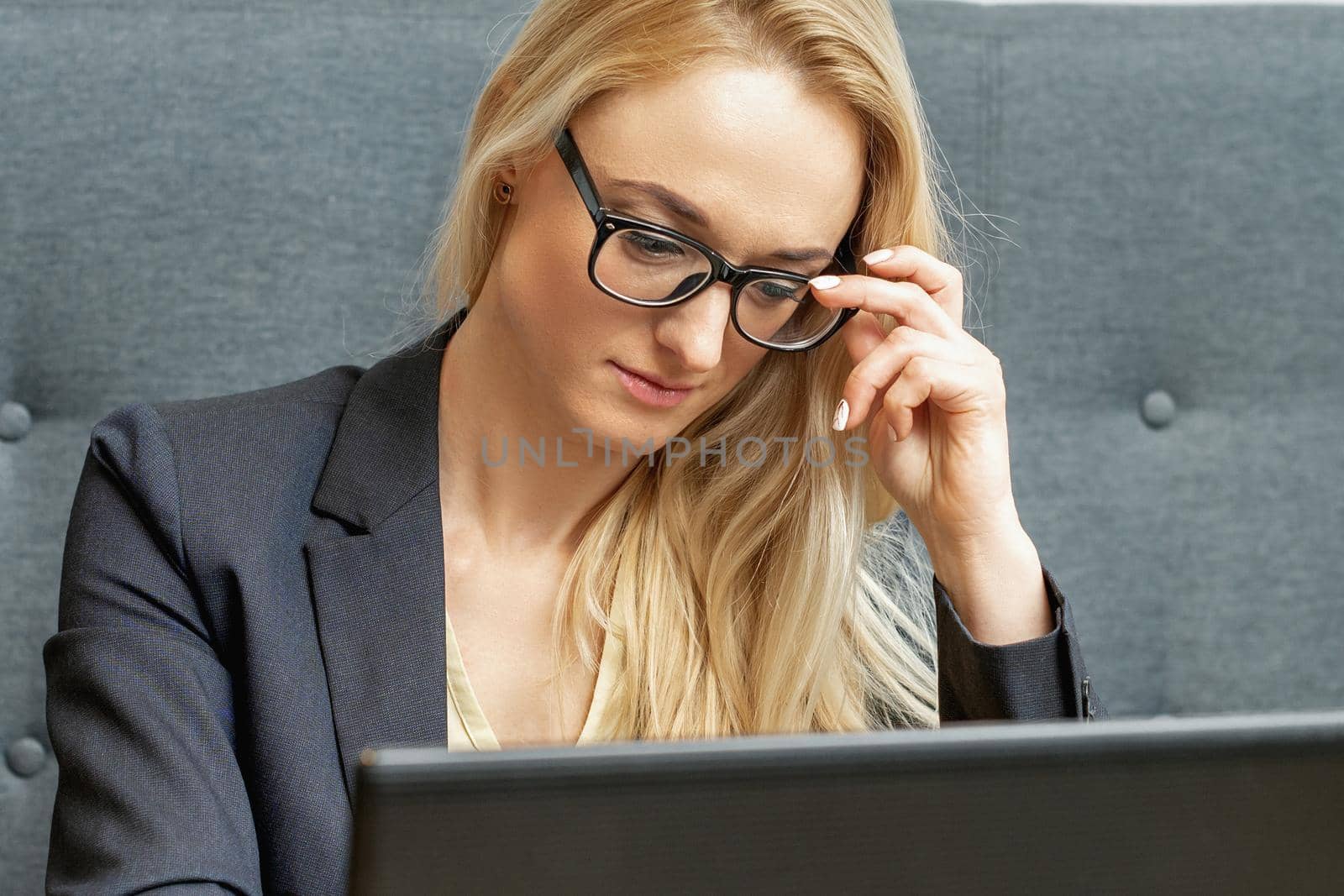 Busy business woman wearing eyeglasses working on laptop at home office.