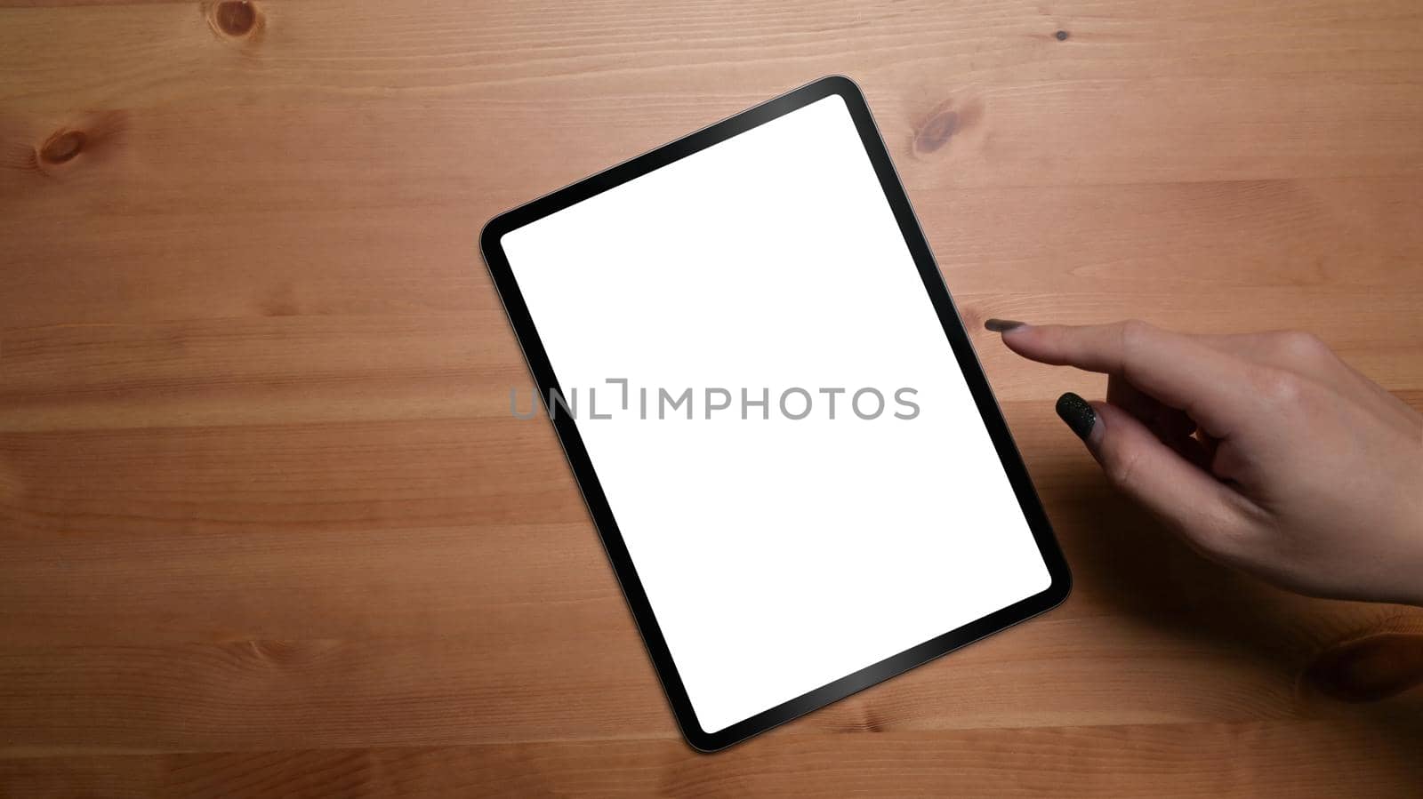 Overhead view woman hand using digital tablet on wooden table.