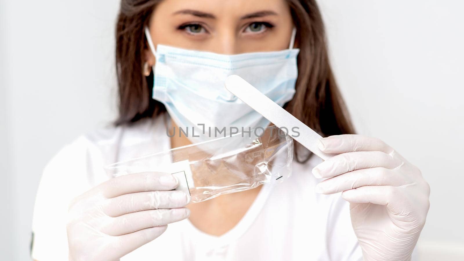 Woman holding medical tool wearing mask in salon.