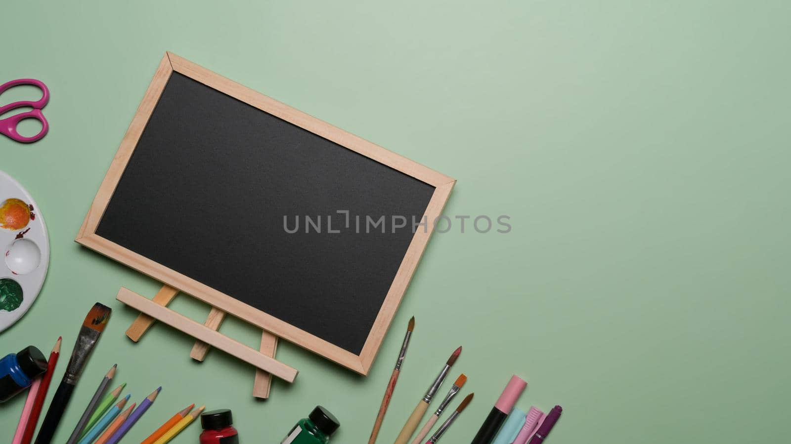 Flat lay empty chalkboard and school stationery on green background. Back to school concept.