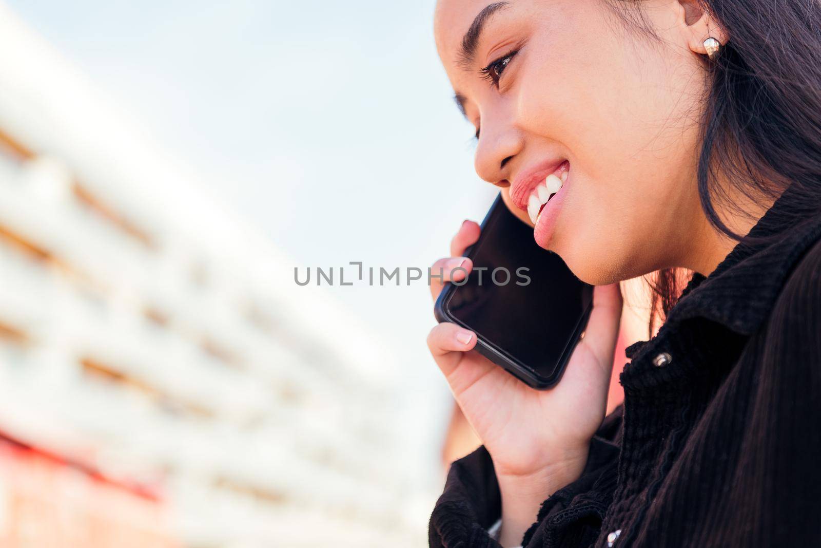 close up portrait of a young asian woman outdoors talking by phone