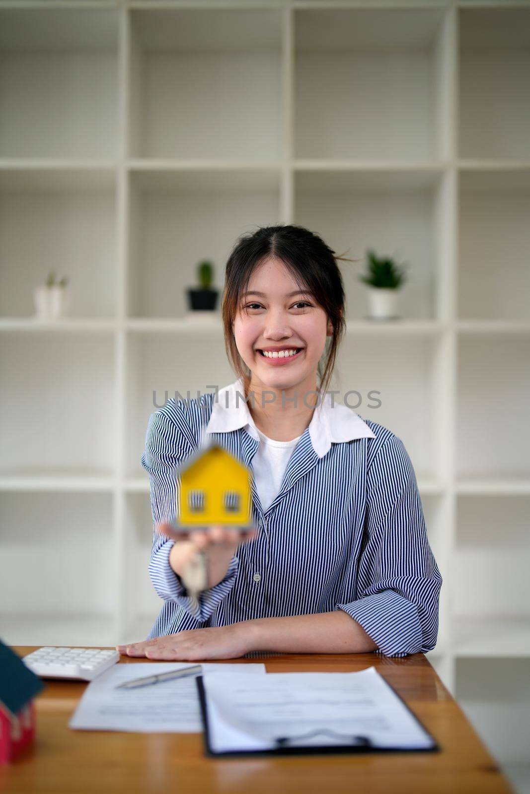 Portrait woman holding house model in hand caontract agreement to buying property