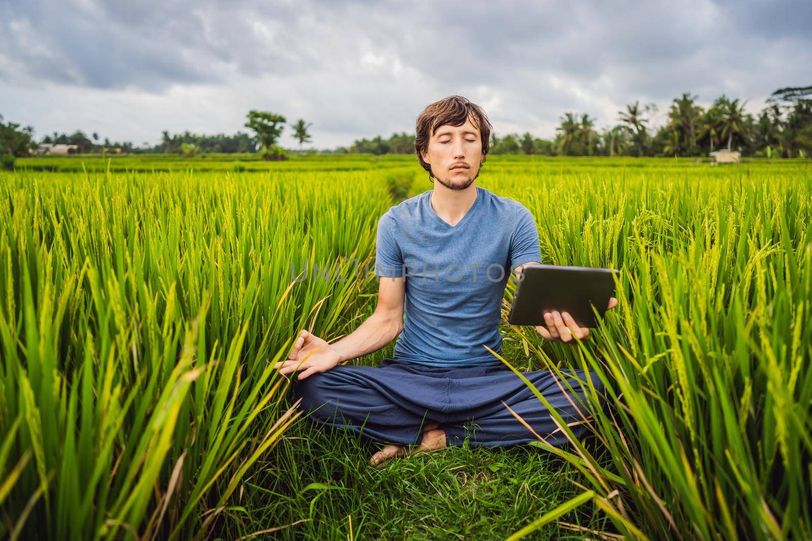 Handsome man learns to do yoga, watch educational video on tablet by galitskaya