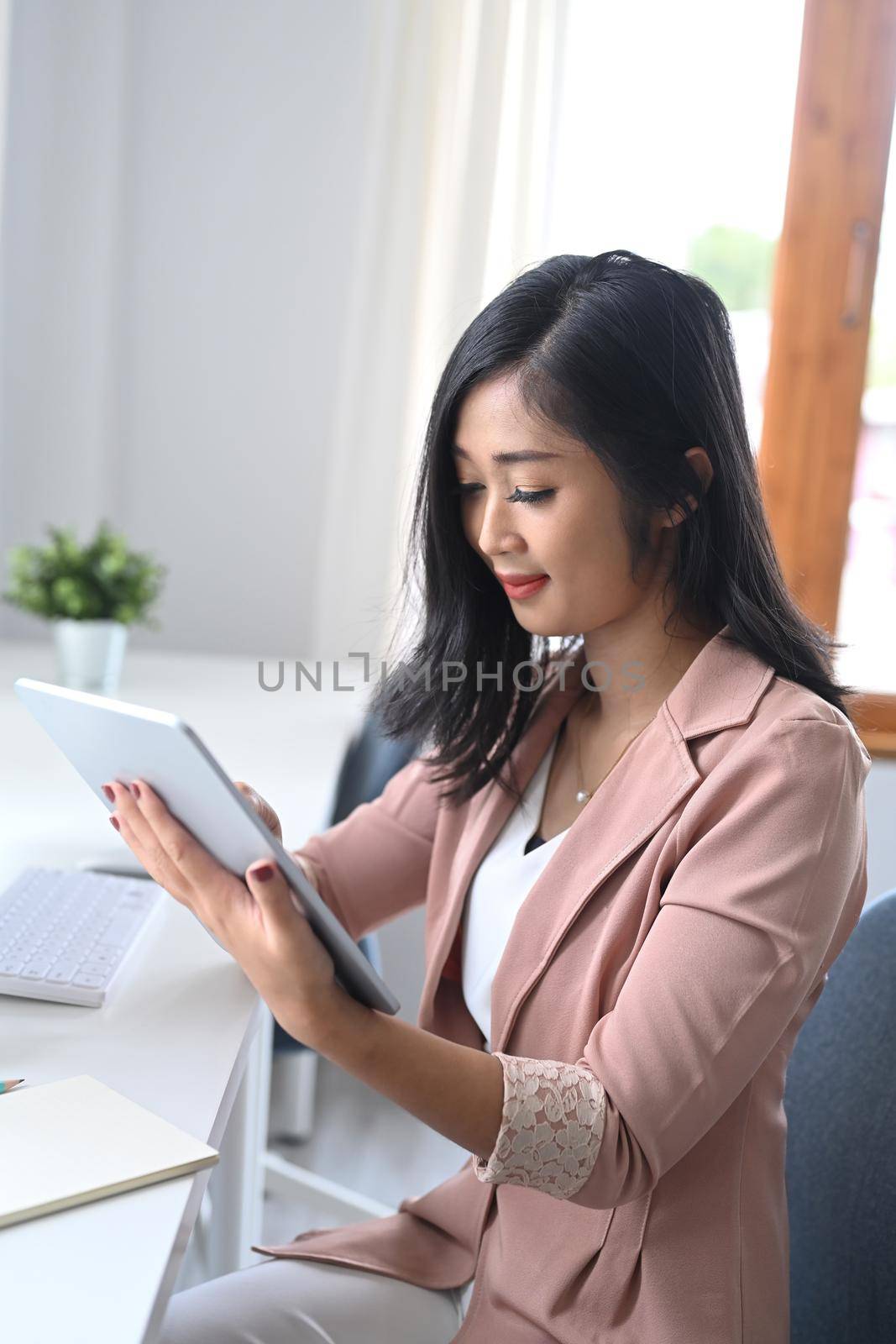 Smiling female entrepreneur checking email on her digital tablet.