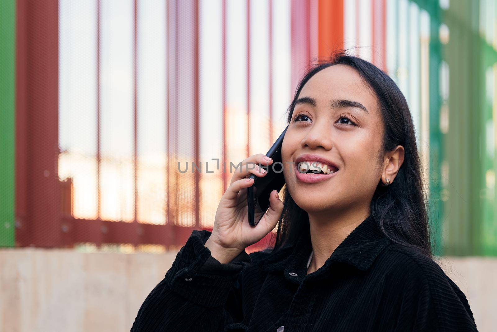 smiling young asian woman talking on the phone outdoors