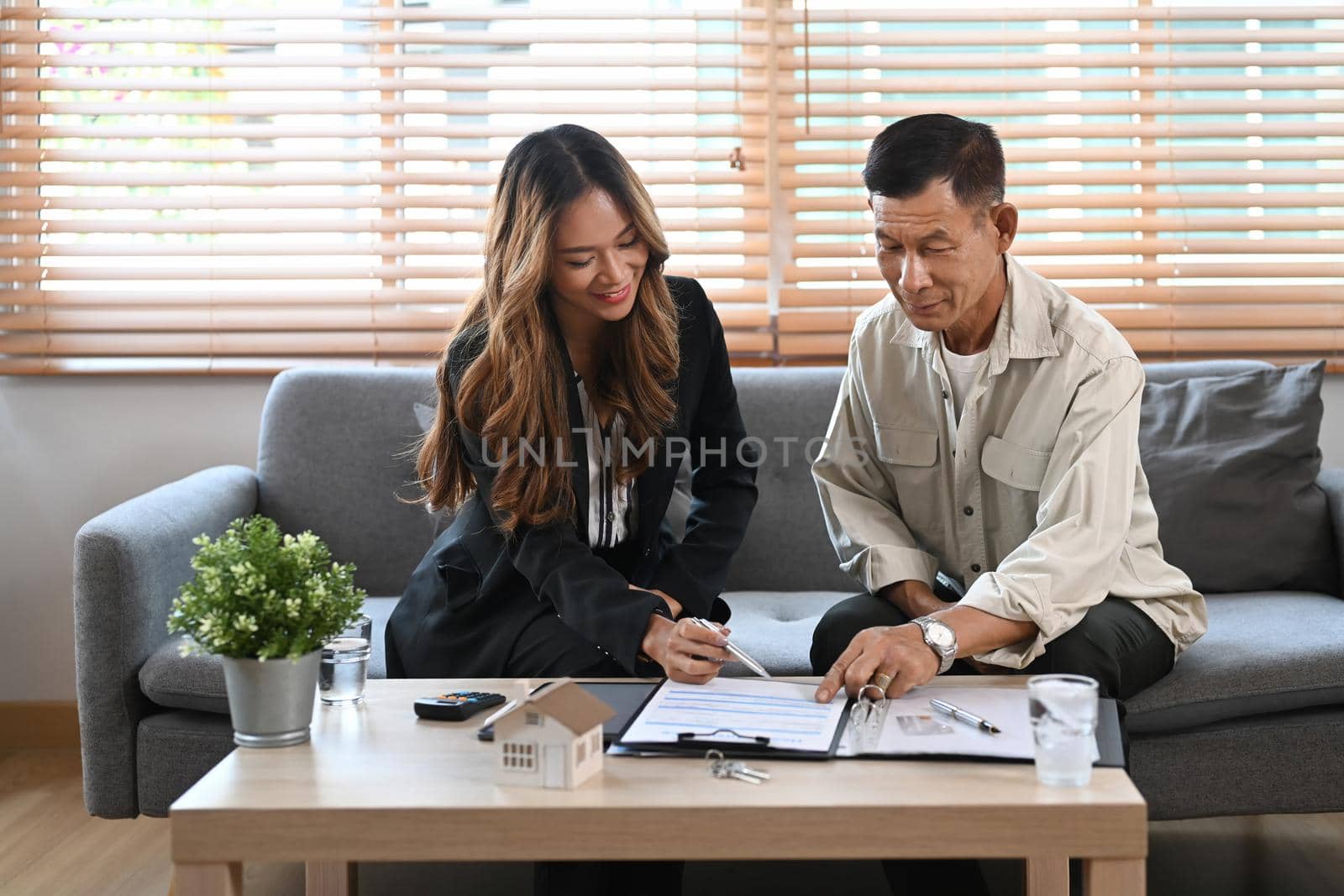 Beautiful female real estate consulting with retired asian male customer.