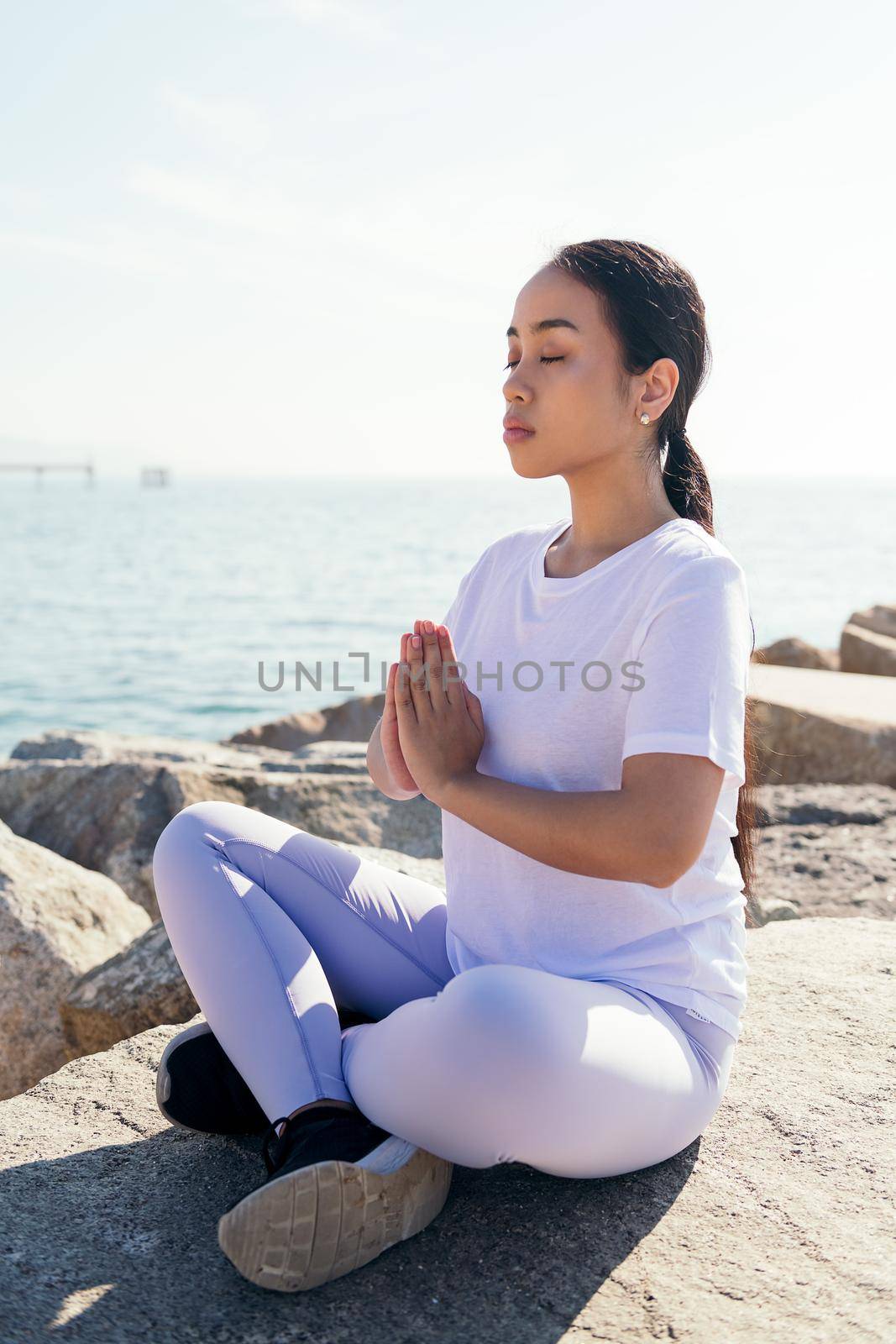 vertical photo of a young asian woman doing a meditation with hands together and eyes closed, concept of spirituality and relax