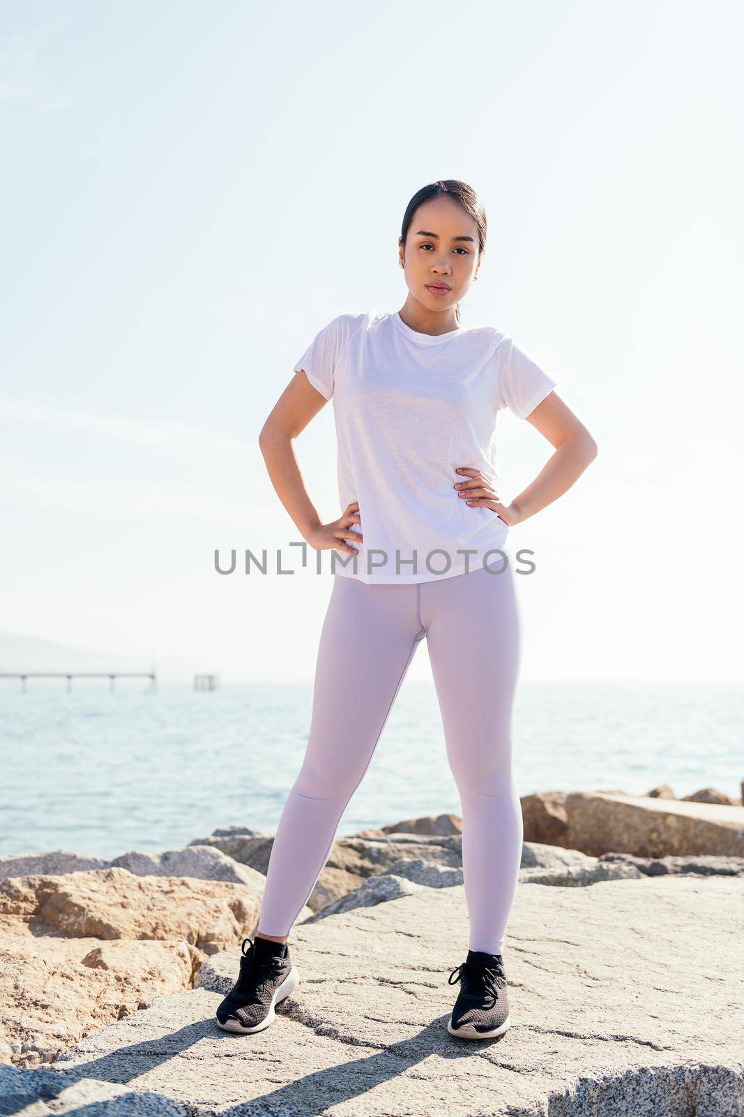 confident young sportswoman looks at camera standing with hands on hips, concept of sport and active lifestyle