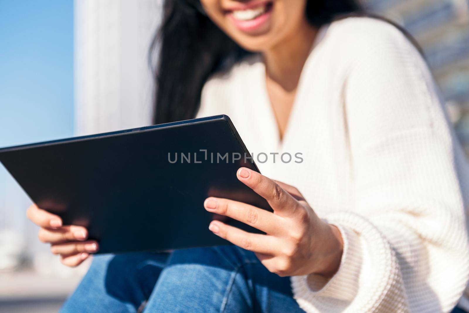 unrecognizable young woman using tablet outdoors, focus on the tablet