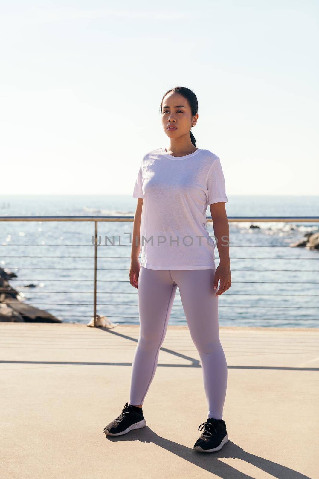 young female athlete concentrating on standing during outdoor workout, concept of sport and active lifestyle
