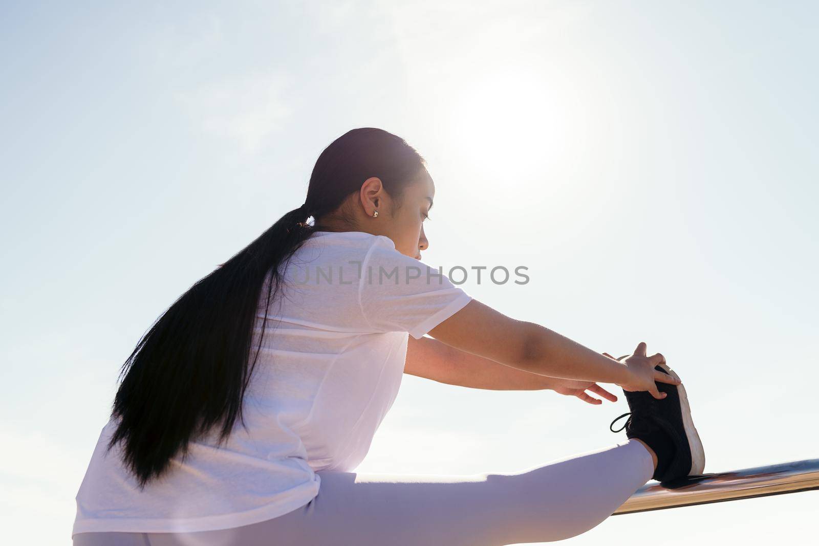 young asian female athlete stretching legs outdoors, concept of sport and active lifestyle