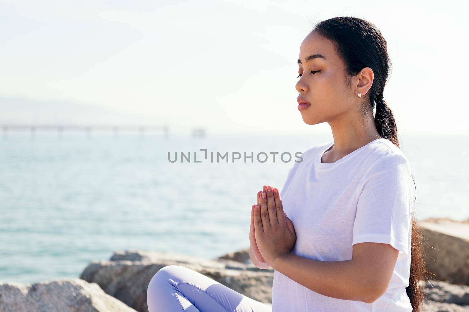 portrait of a young asian woman meditating outdoors in calm with hands together and eyes closed, concept of spirituality and relax