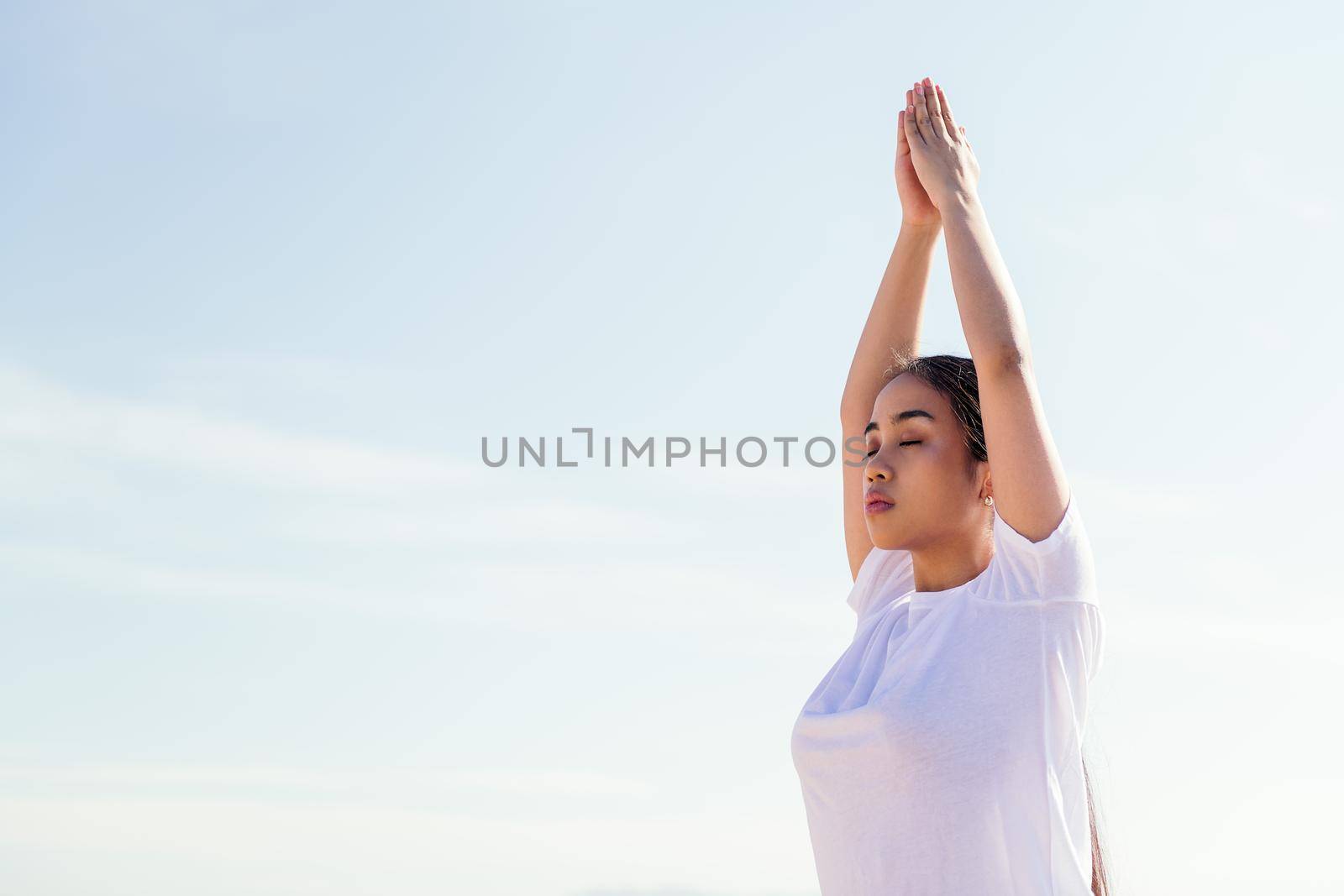 portrait of a young asian woman meditating practicing yoga with her eyes closed, concept of spirituality and relax