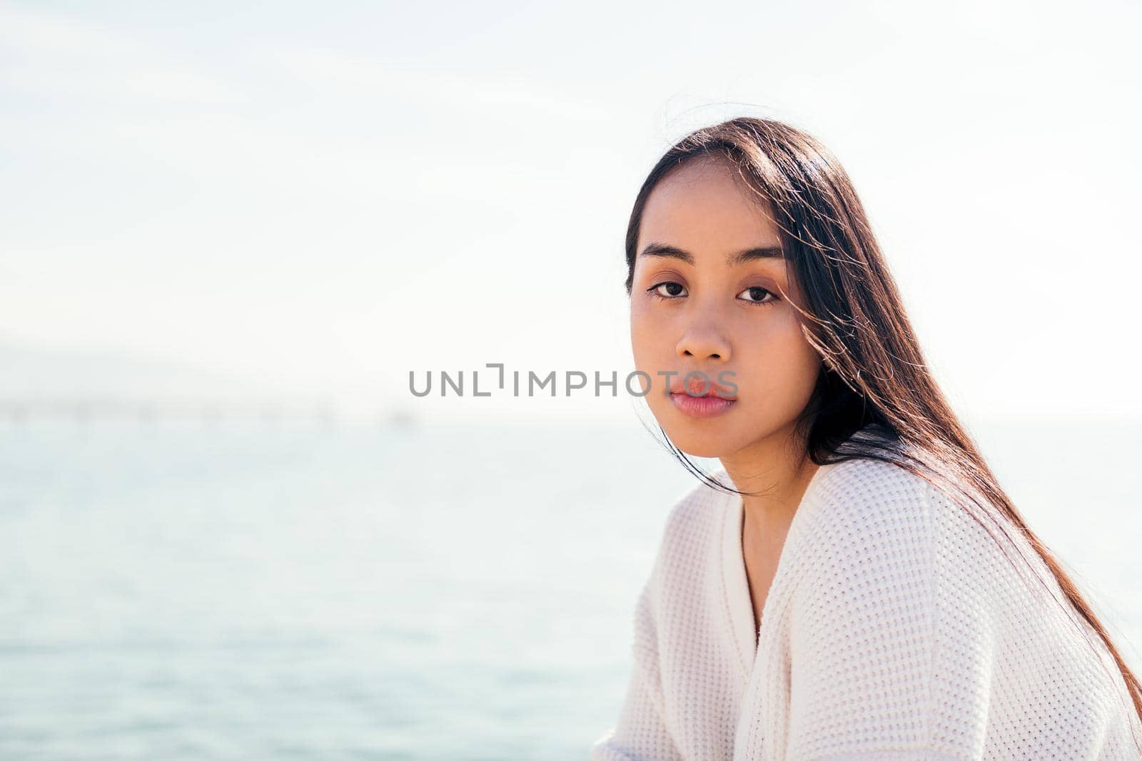 young asian woman dressed in white looking at camera with serious and relaxed expression, concept of beauty and purity