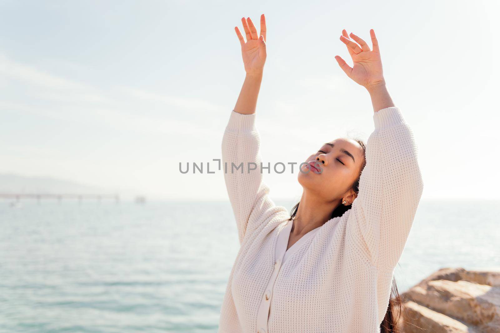 young asian woman dressed in white dances free and carefree by the sea, concept of beauty and purity